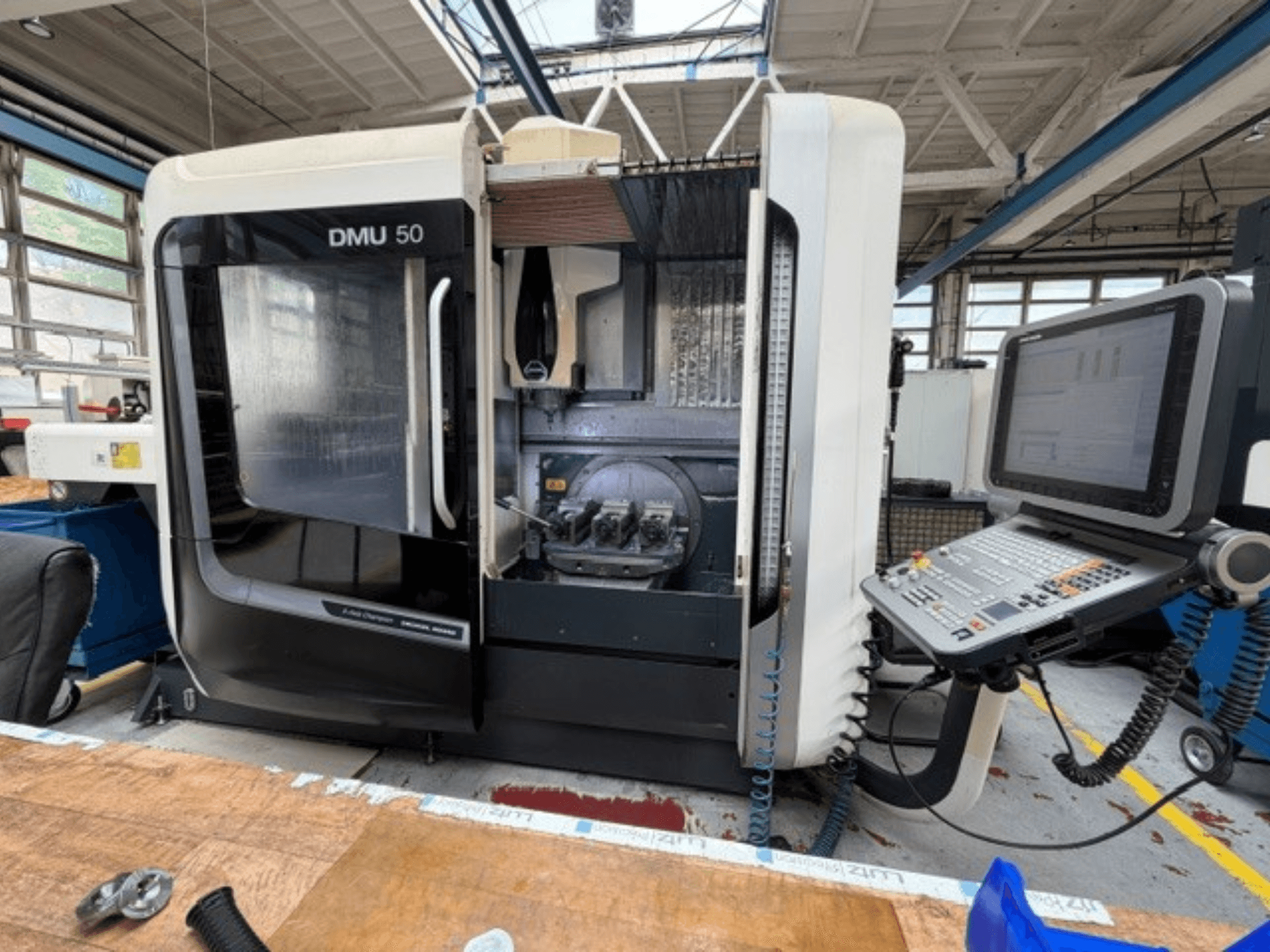 DMG MORI DMU 50, vertikalt bearbetningscenter av tredje generationen, sett framifrån, med öppen lucka, synlig CNC-kontrollpanel och arbetsutrymmet inuti.