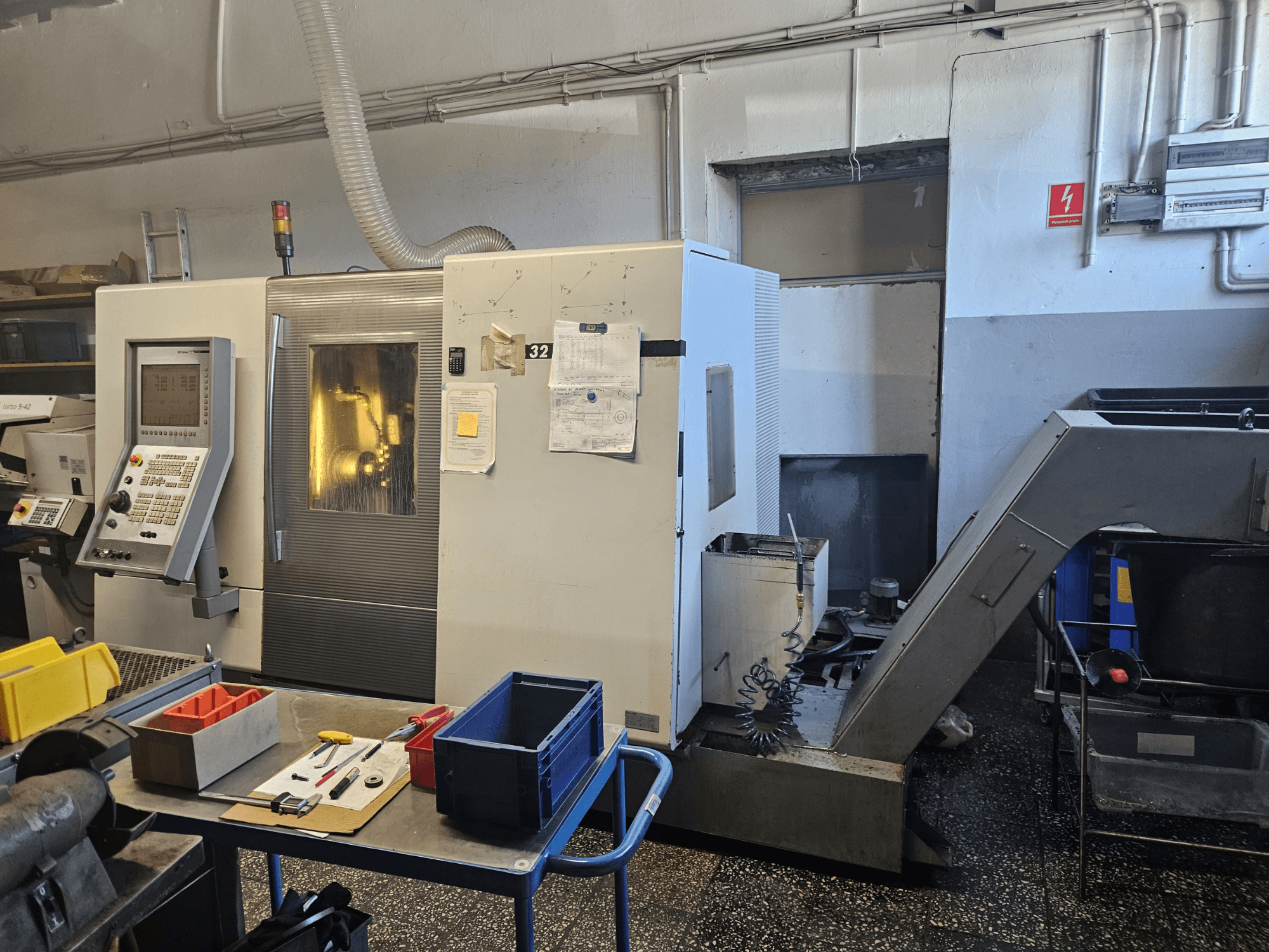 Flerspindlig svarv DMG GILDEMEISTER Sprint 32 linear, framifrån i en verkstad, med kontrollpanel och verktyg synliga.