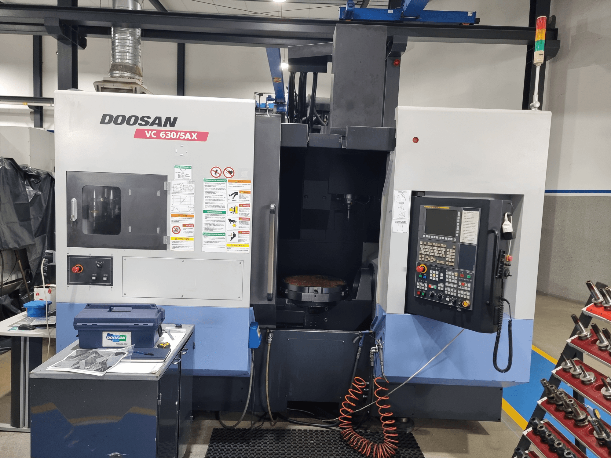 DOOSAN VC 630/5AX universellt bearbetningscenter, framifrån med kontrollpanelen, bearbetningsområdet och säkerhetsfunktionerna i förgrunden.