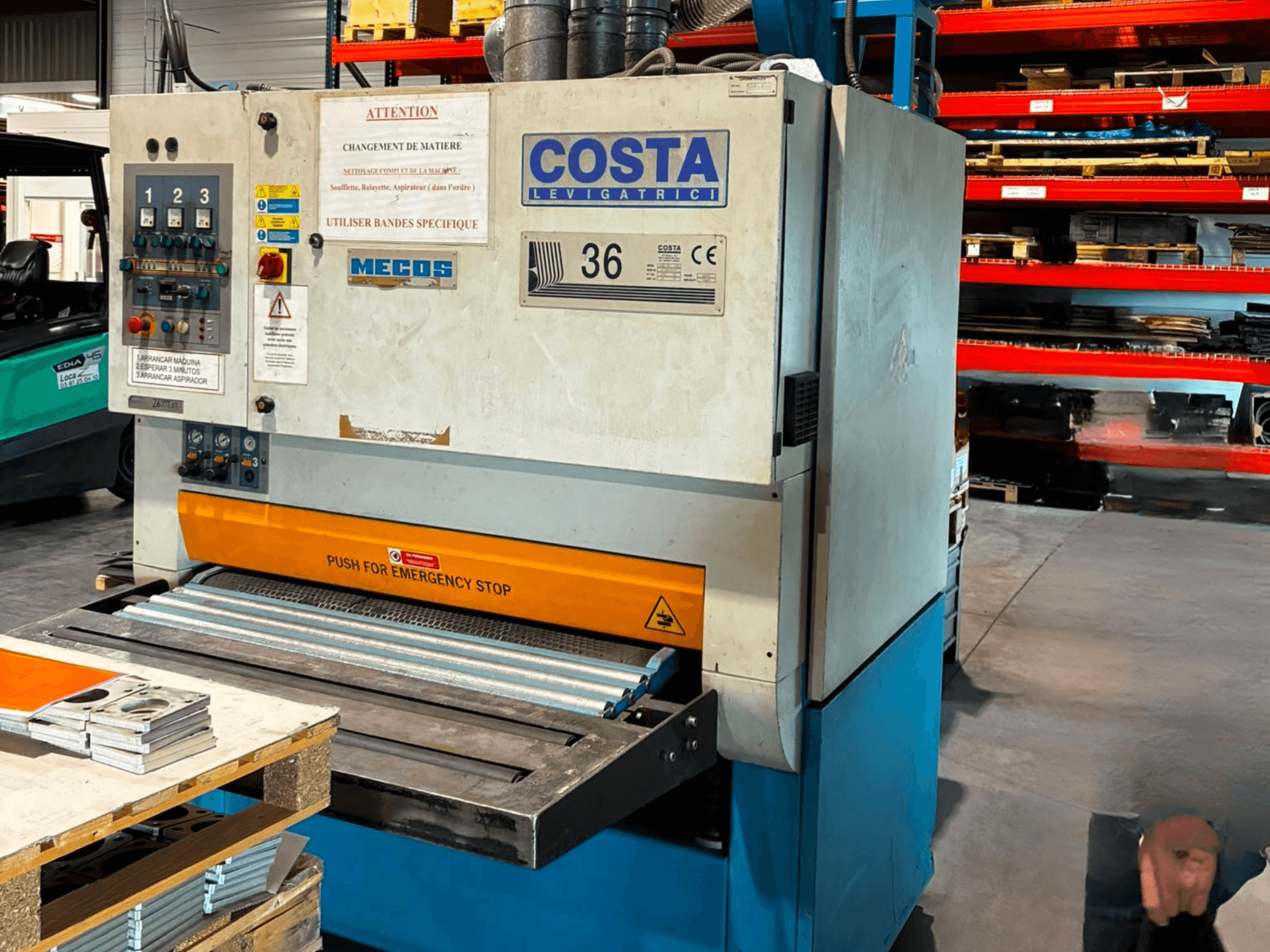 Avgradningsmaskin av typen Costa M36 CCS 1150 sett från sidan, med kontrollpanel, nödstopp och transportband.