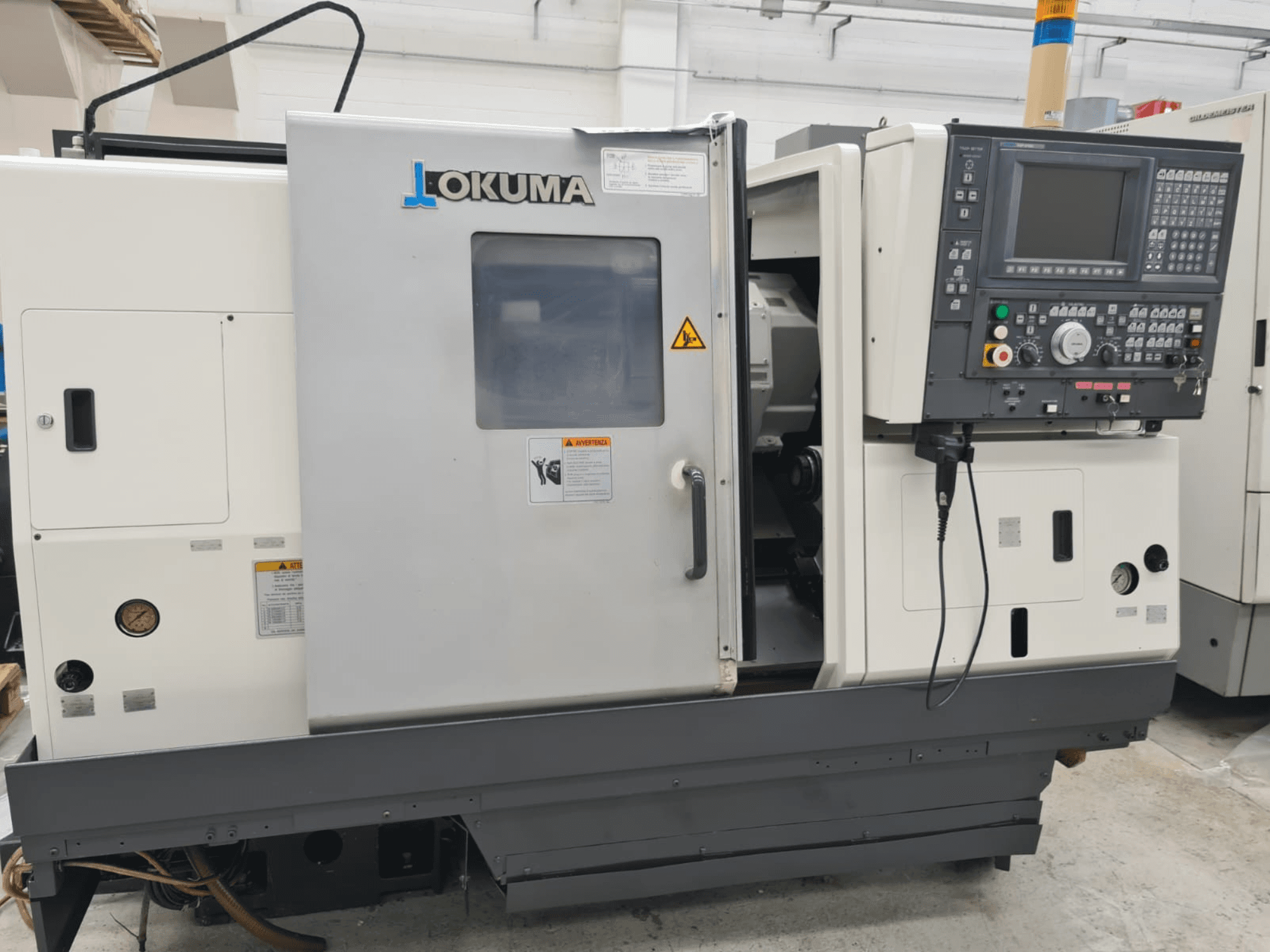 Okuma LB 300M X 500 horisontell svarv i sidovy, visar kontrollpanelen, spindelåtkomst och säkerhetsvarningar.