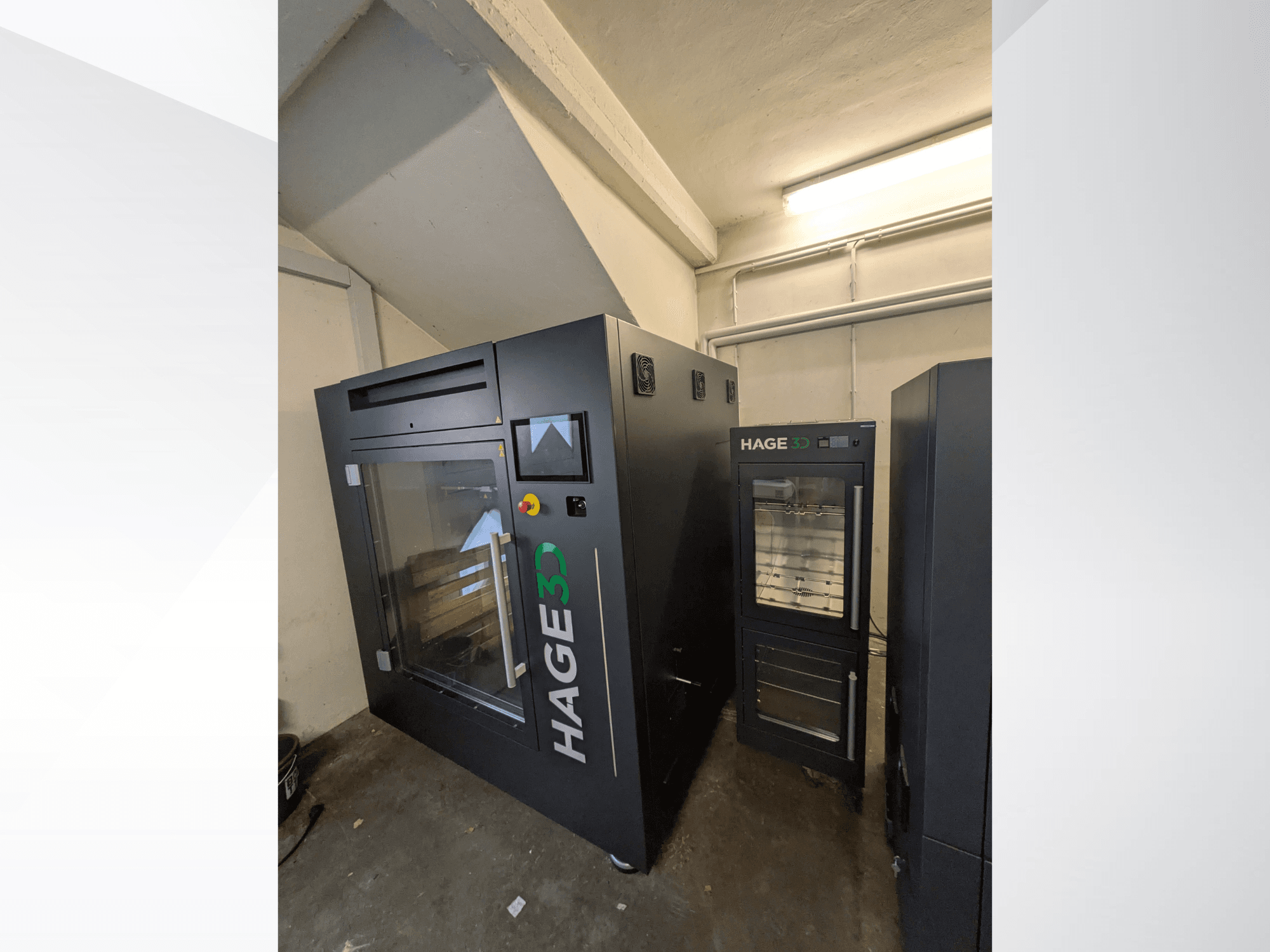 En HAGE 3D Precision One 3D-skrivare i plast, sedd från sidan, med en genomskinlig lucka och kontrollpanel samt förvaringsutrymme bredvid.