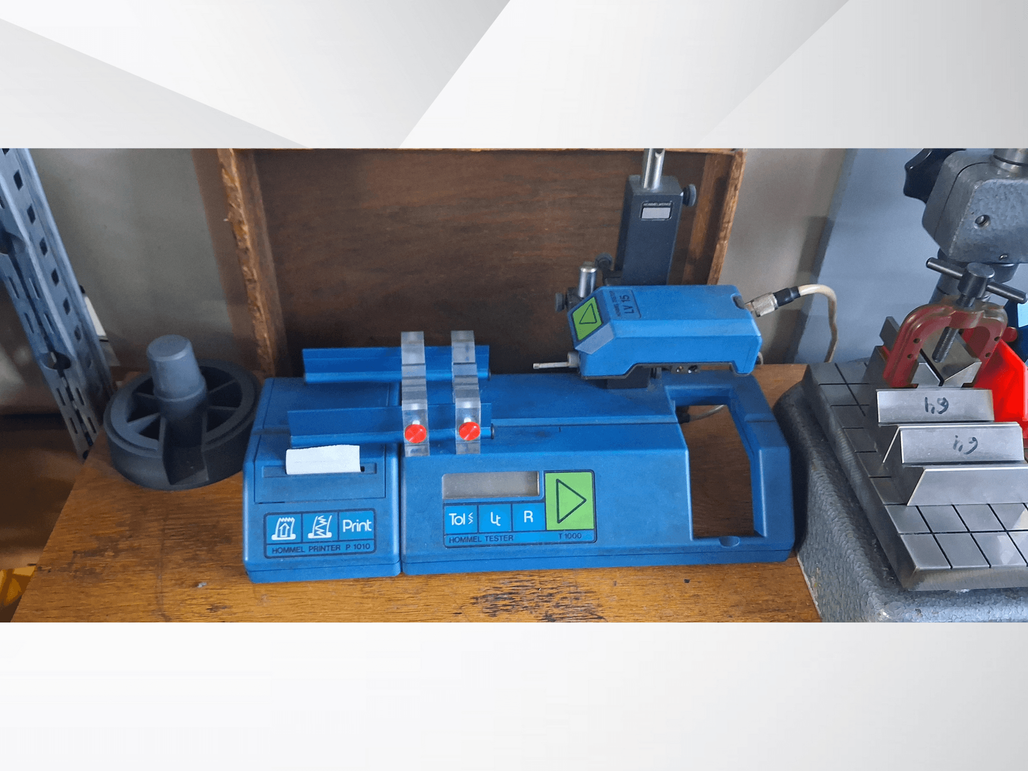 Hommel Printer P 1010 och Tester T1000 i sidovy, med blått hölje, knappar och röda indikatorer, på en arbetsbänk.