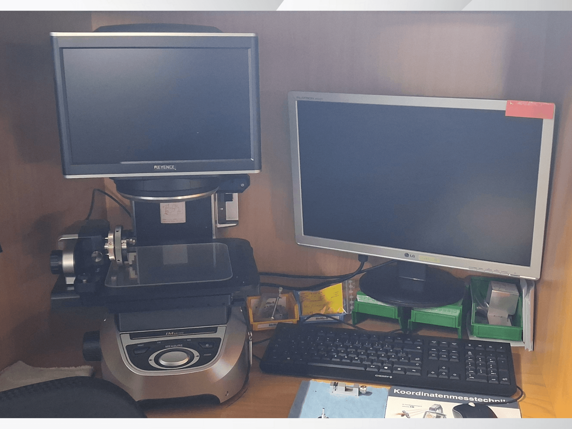 Keyence-mätsystem med två bildskärmar (en LG, en Keyence) och ett tangentbord, sett framifrån.