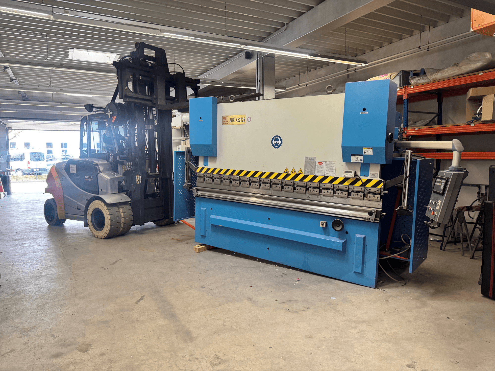 Hydraulisk press KNUTH AHK A 32125 i en verkstad, sidovy som visar kontrollpanel och säkerhetsfunktioner.