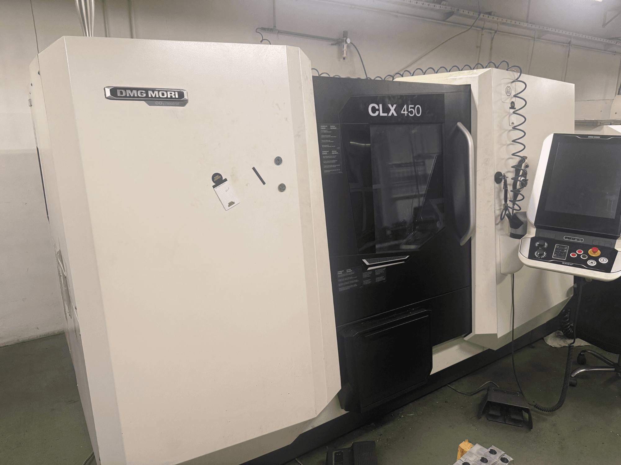 DMG MORI CLX 450 CNC-maskin, sidovy med kontrollpanel, synliga manöverknappar och ren arbetsyta.