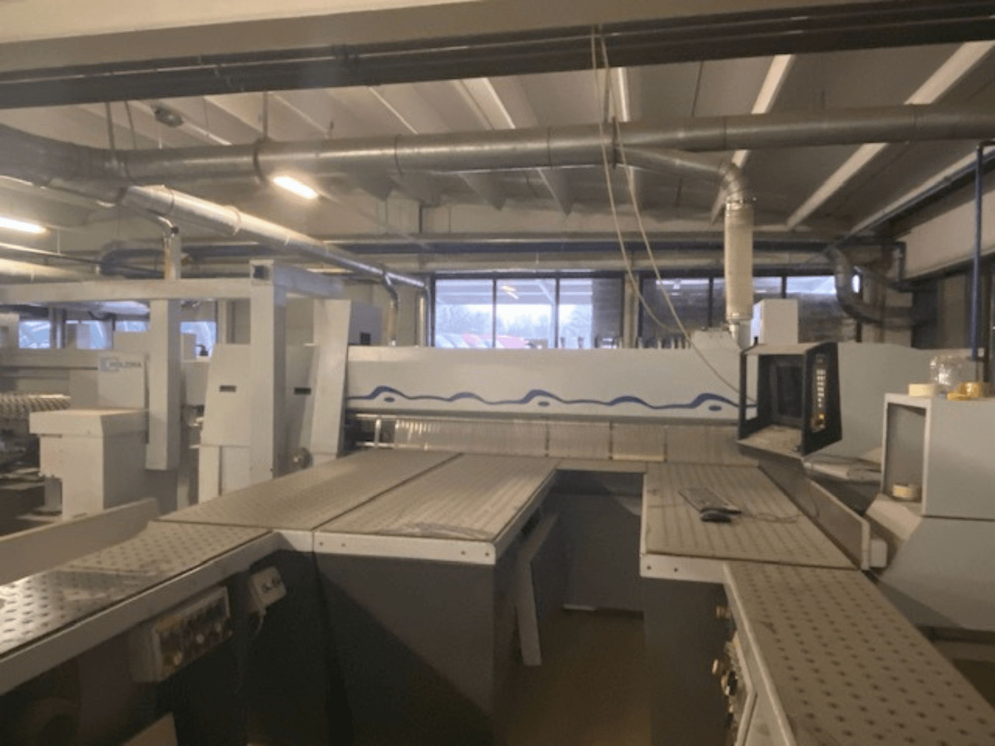 Industriellt arbetsutrymme med en maskinuppställning med kontrollpanel, sett från en upphöjd vinkel framifrån.