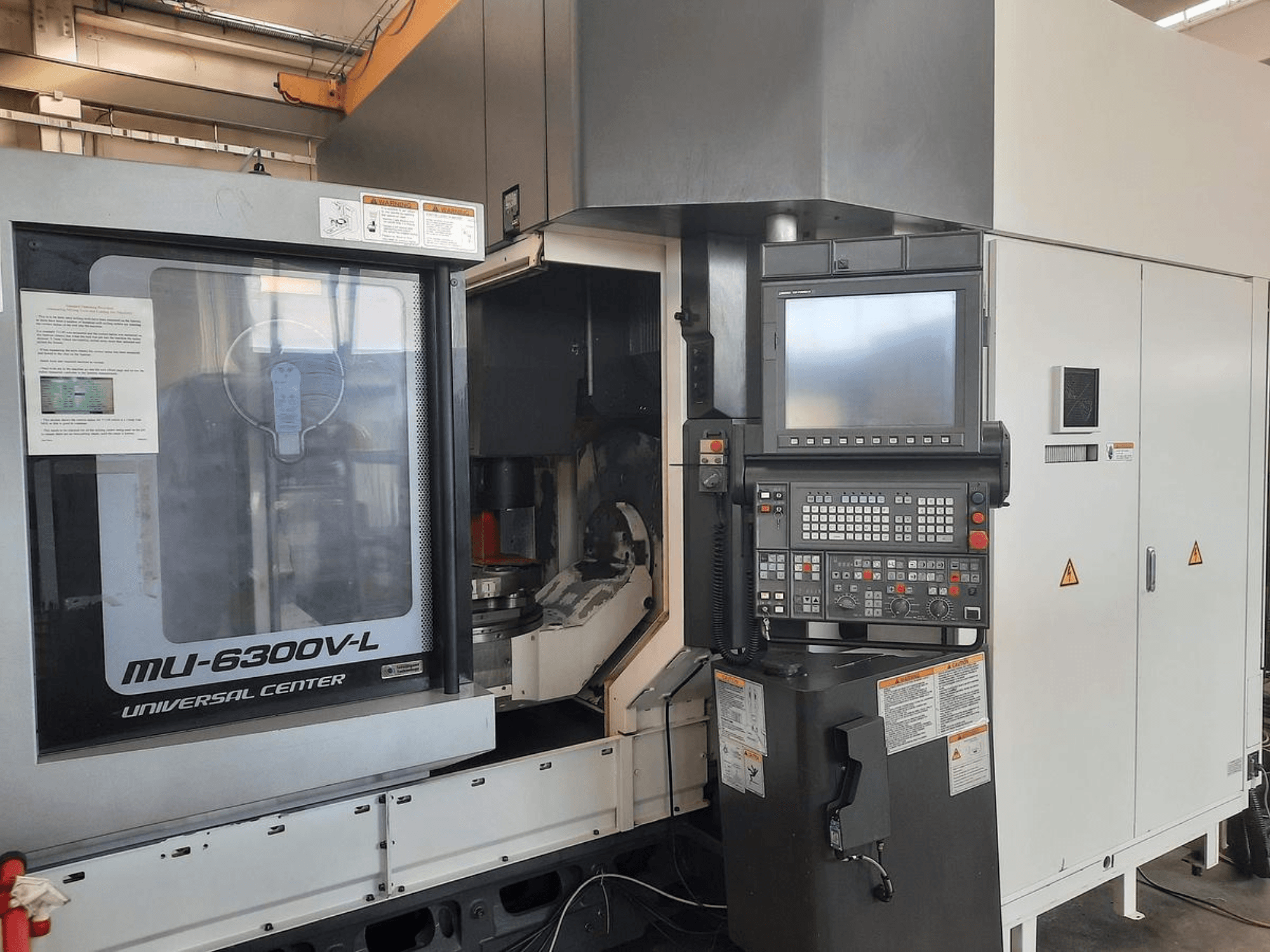 MU-6300V-L Universal Center-maskin visad framifrån, med kontrollpanel, skärm och bruksanvisningar synliga.