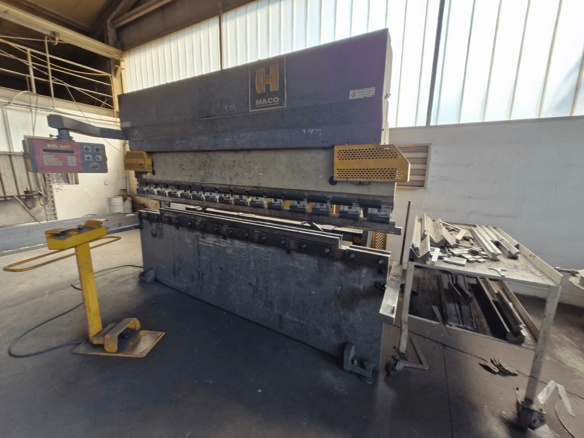 HACO PPM 30135 b kantpress i en verkstad, framifrån med kontrollpanel och metallskrot på ett bord bredvid.