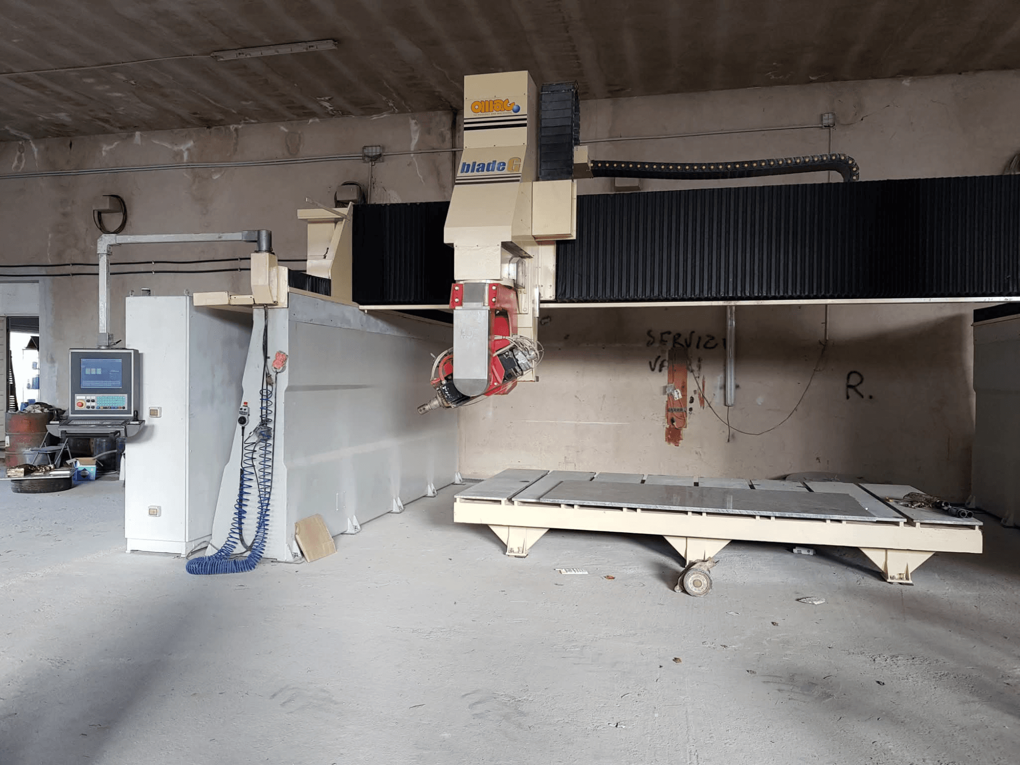 Portalfräsmaskin OMAG Blade G i en verkstad, framifrån med kontrollpanelen och den stora fräsbädden synlig.