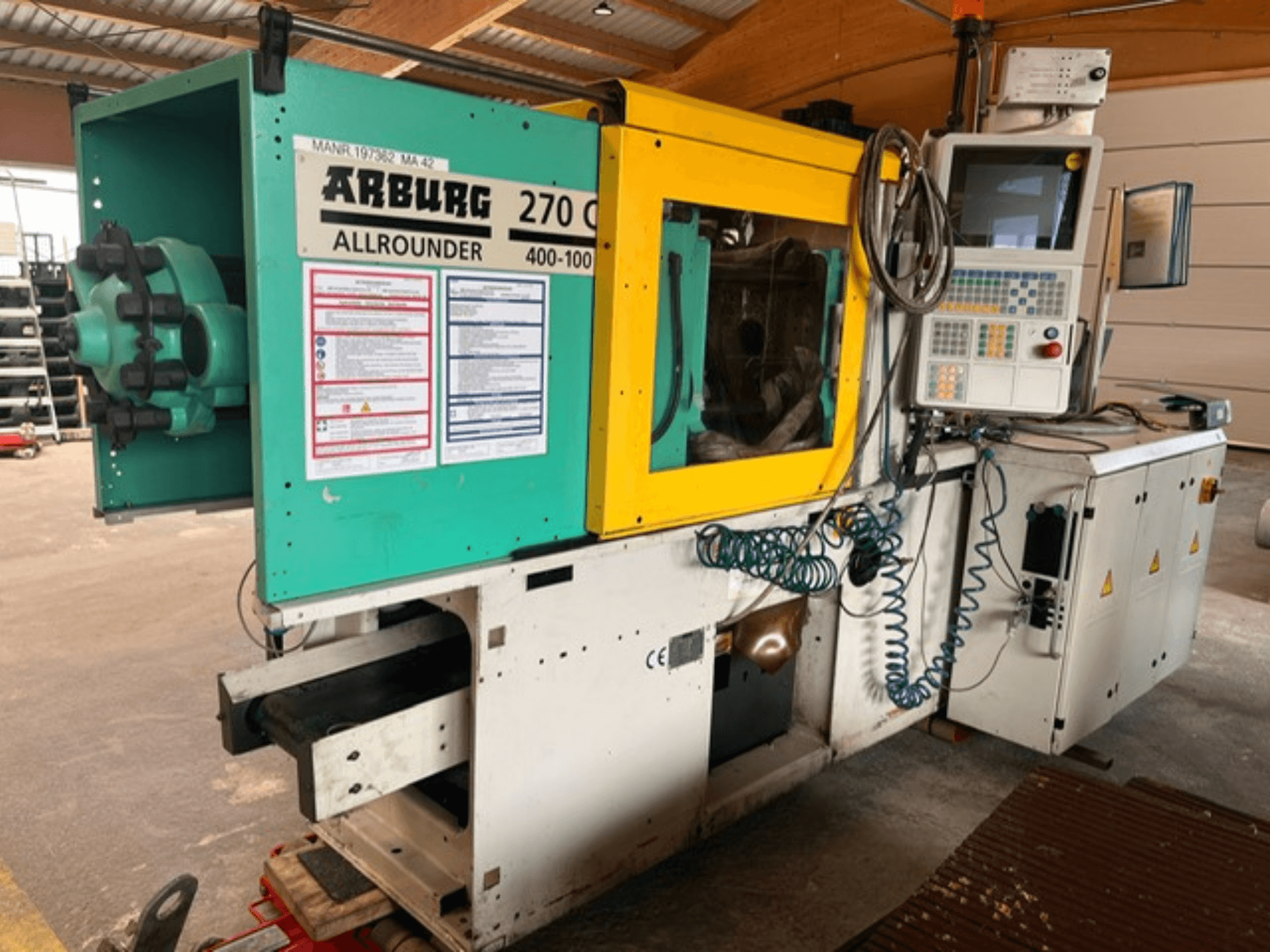 Framifrånvy av den hydrauliska formsprutningsmaskinen Arburg 270 C, med kontrollpanelen och driftsdetaljer.