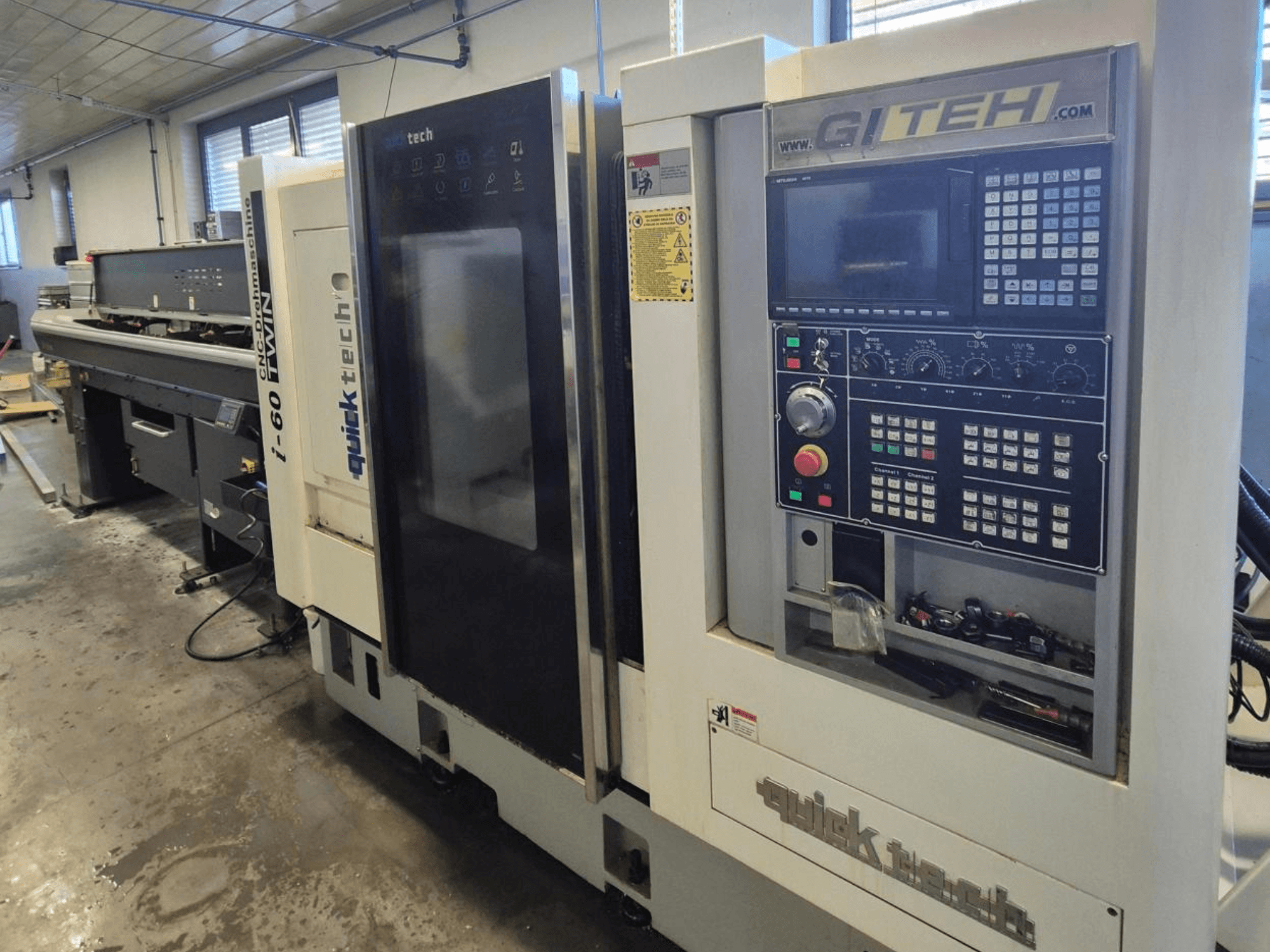 Quick Tech i-60 dubbel CNC-maskin, framifrån, med GITEH-kontrollpanel och manöverknappar, i en verkstadsmiljö.