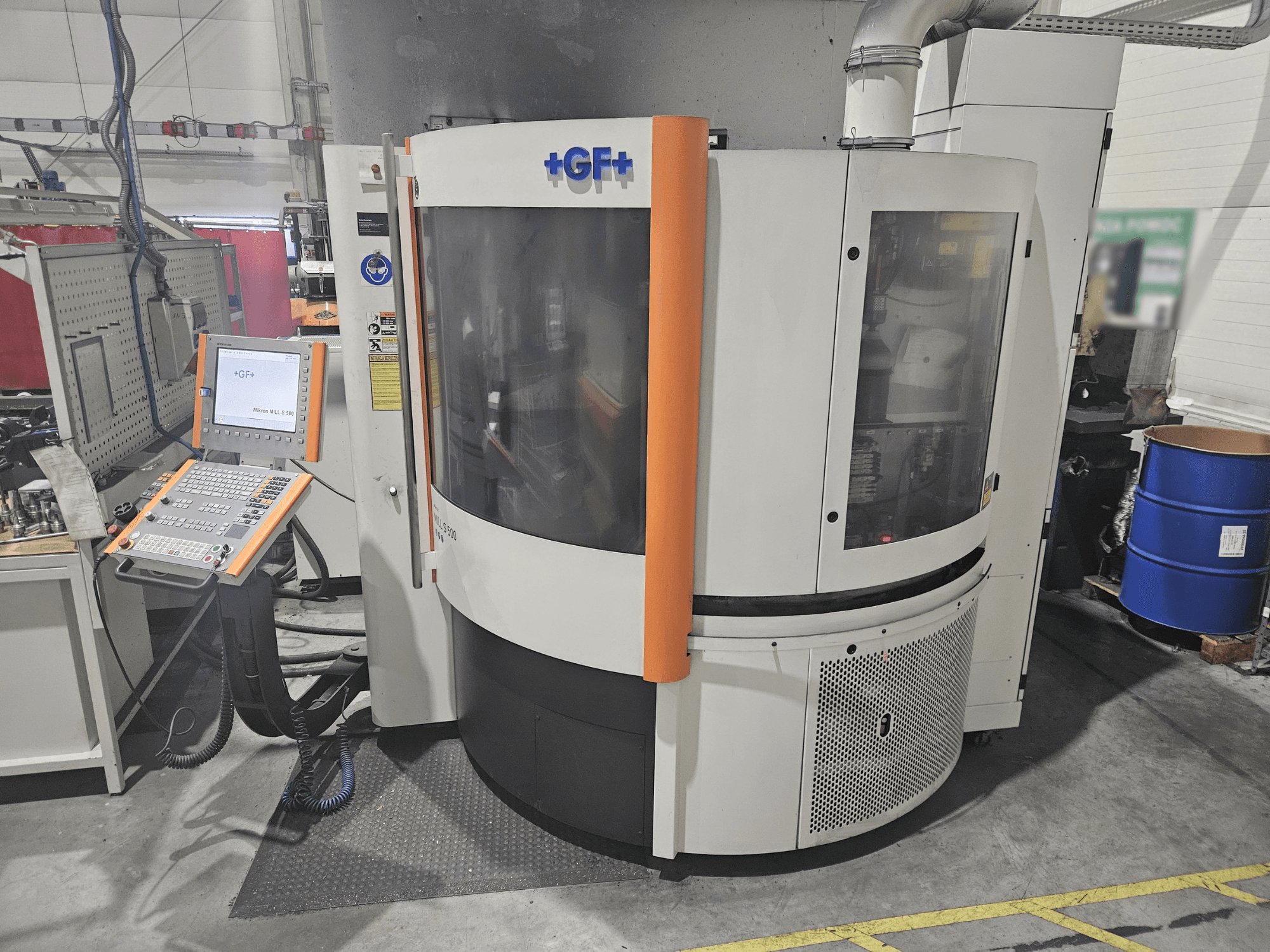 GF Machining Solutions verktygsmaskin med kontrollpanel, framifrån; har transparent panel, orangefärgade accenter och industriell miljö.