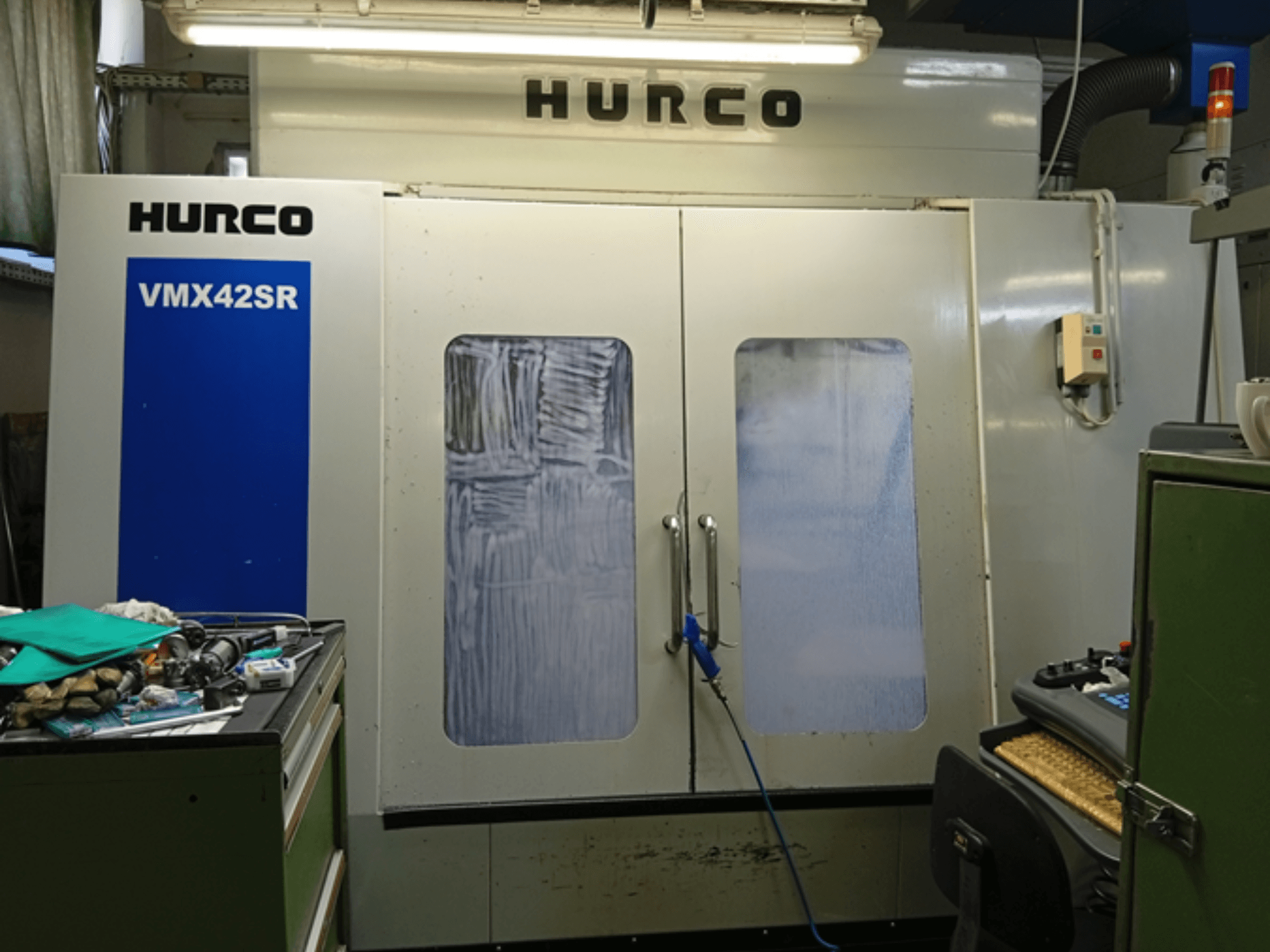 Hurco VMX 42SR vertikal fleroperationsmaskin framifrån, med blå panel, kontrollgränssnitt och ren arbetsyta.