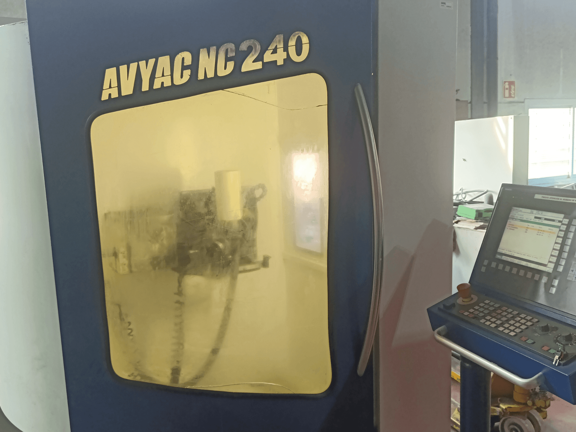 AVYAC NC240 rundslipmaskin, sidovy med kontrollpanel och delvis synligt slipområde genom fönstret.