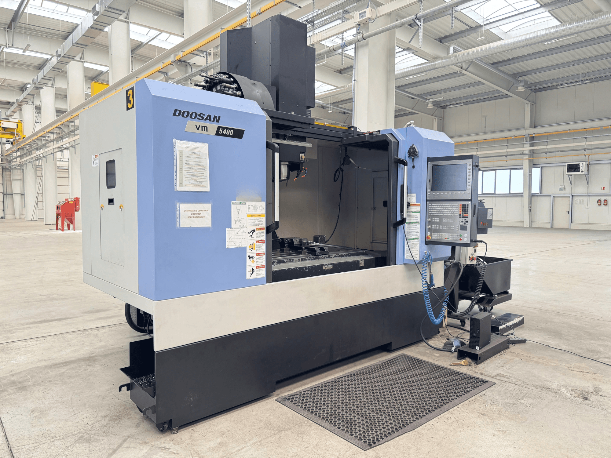 DOOSAN VM 5400 Vertikal bearbetningscenter, framifrån med kontrollpanel och arbetsområde i rymlig industrimiljö.