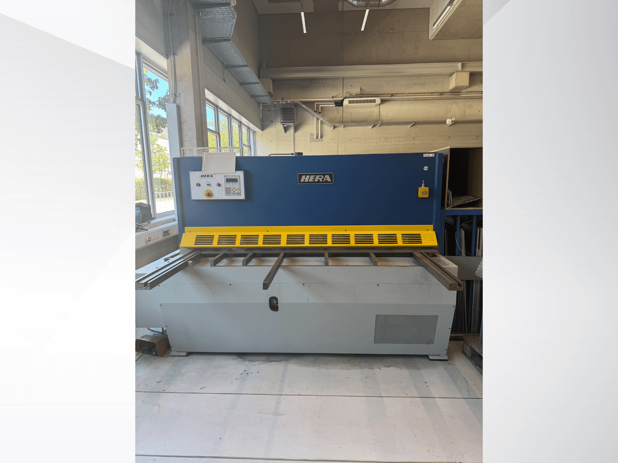 Hydraulisk skärmaskin HERA TS 2000x6 sett framifrån, i blått och gult utförande med manöverpanel och skärbänk.