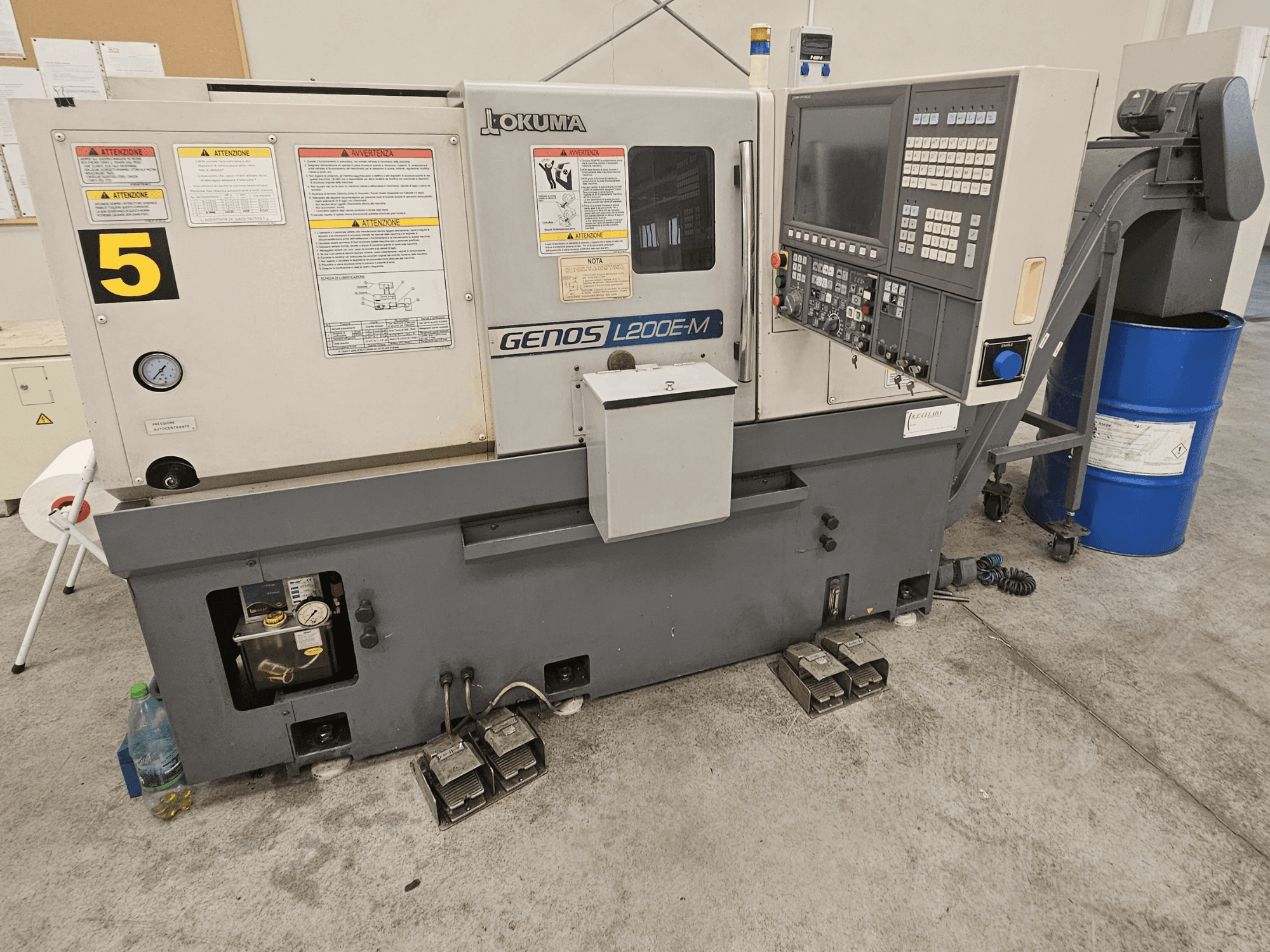 Okuma GENOS L200E-M horisontell svarv framifrån, med kontrollpanel, etiketter och kylvätsketub.