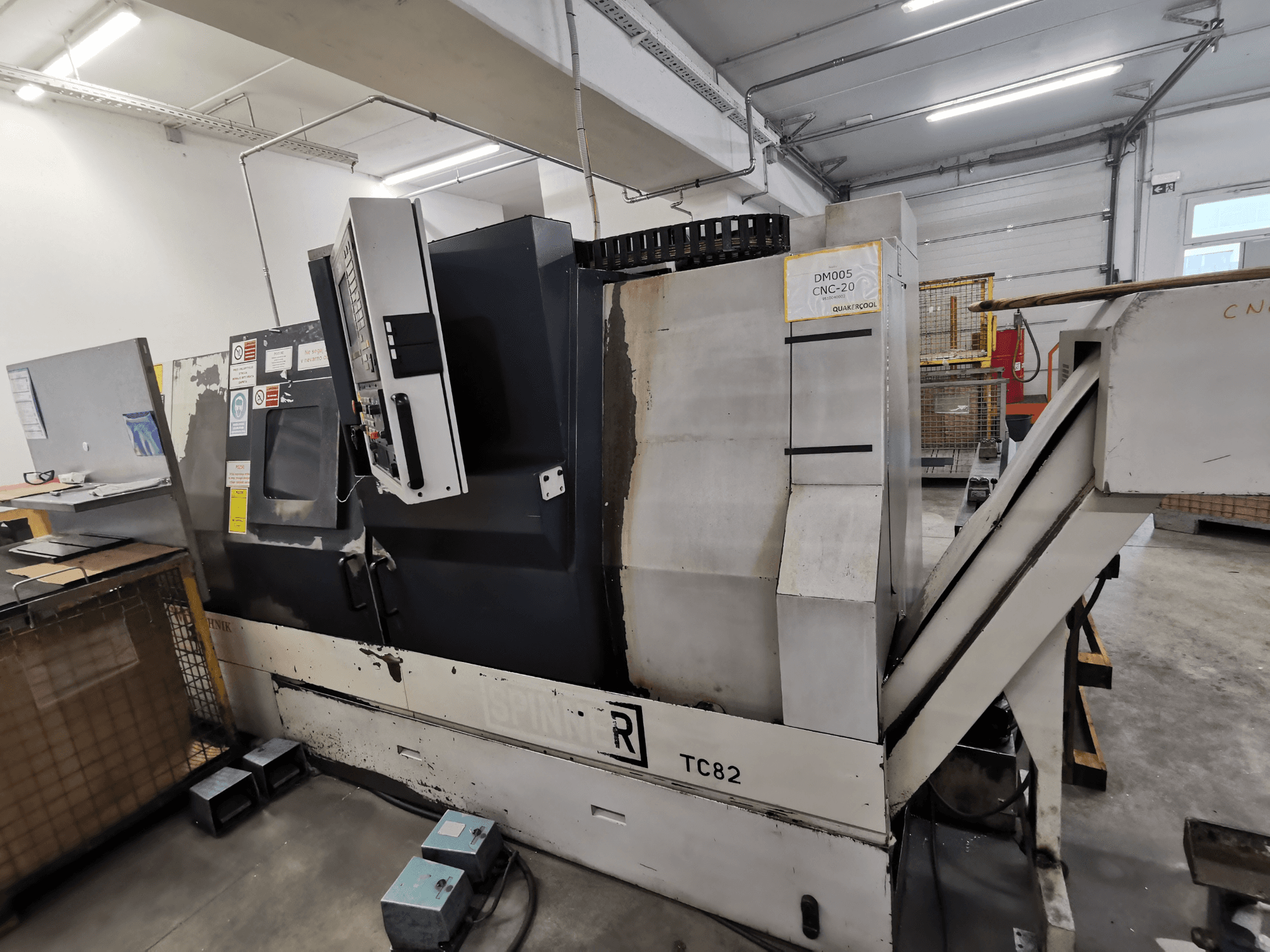 CNC-maskin, märke Spinner, modell TC82, sidovy som visar kontrollpanelen och skrotuppsamlingsrännan i en verkstadsmiljö.