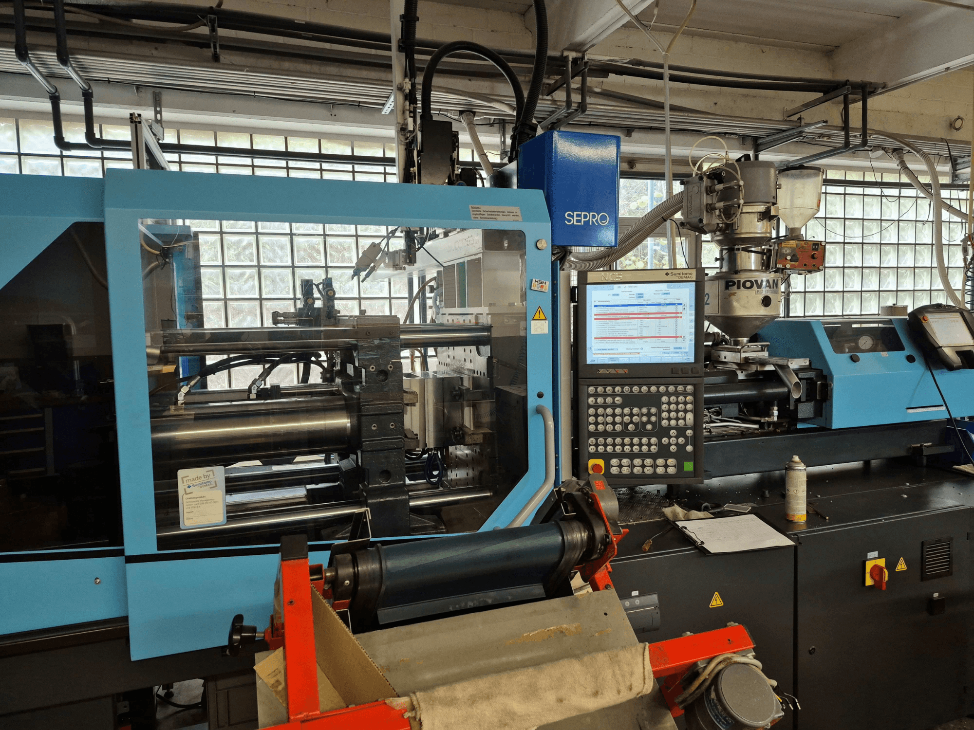 Hydraulisk formsprutningsmaskin SUMITOMO SHI DEMAG Systec 120/470-430, framifrån sett med kontrollpanelen och matningssystemet synliga.