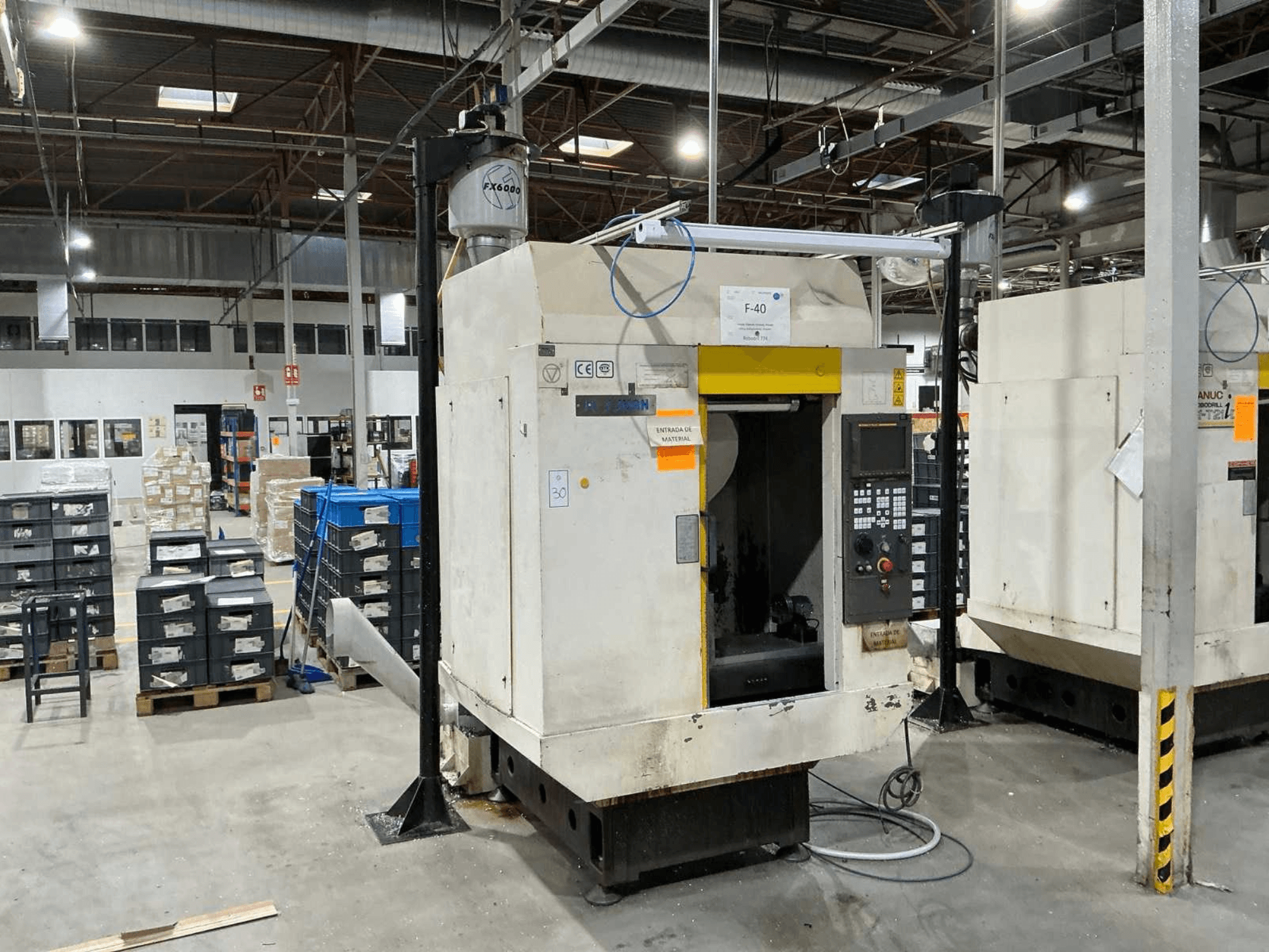 FANUC ROBODRILL α-T21iD, frontvy av vertikalt bearbetningscenter i en industriell miljö, med detaljer på kontrollpanelen synliga.