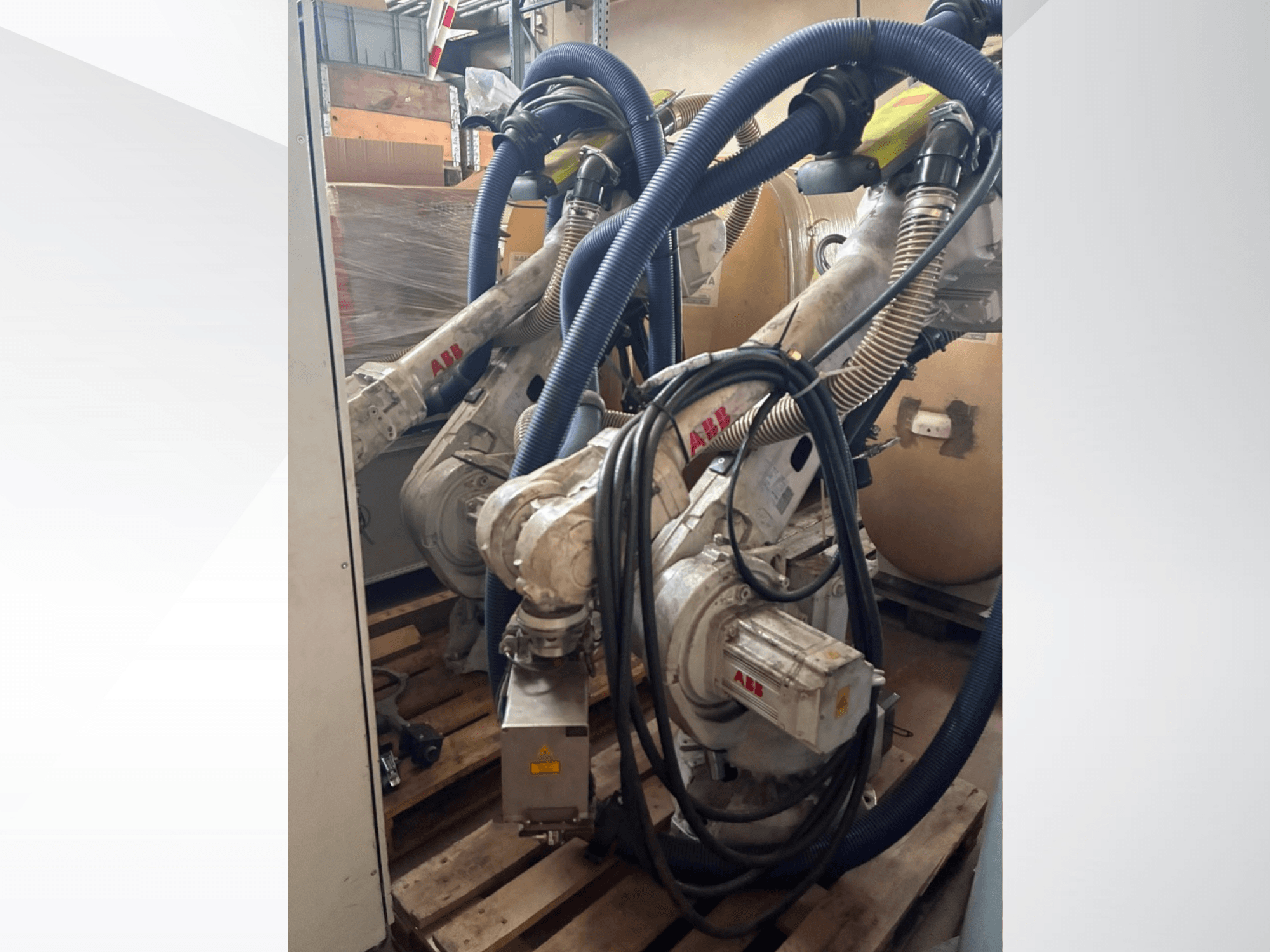 ABB IRB 4600-40/2,55 robotarm, sidovy som visar de två armarna och anslutna slangar, monterad på pallar i en lagermiljö.