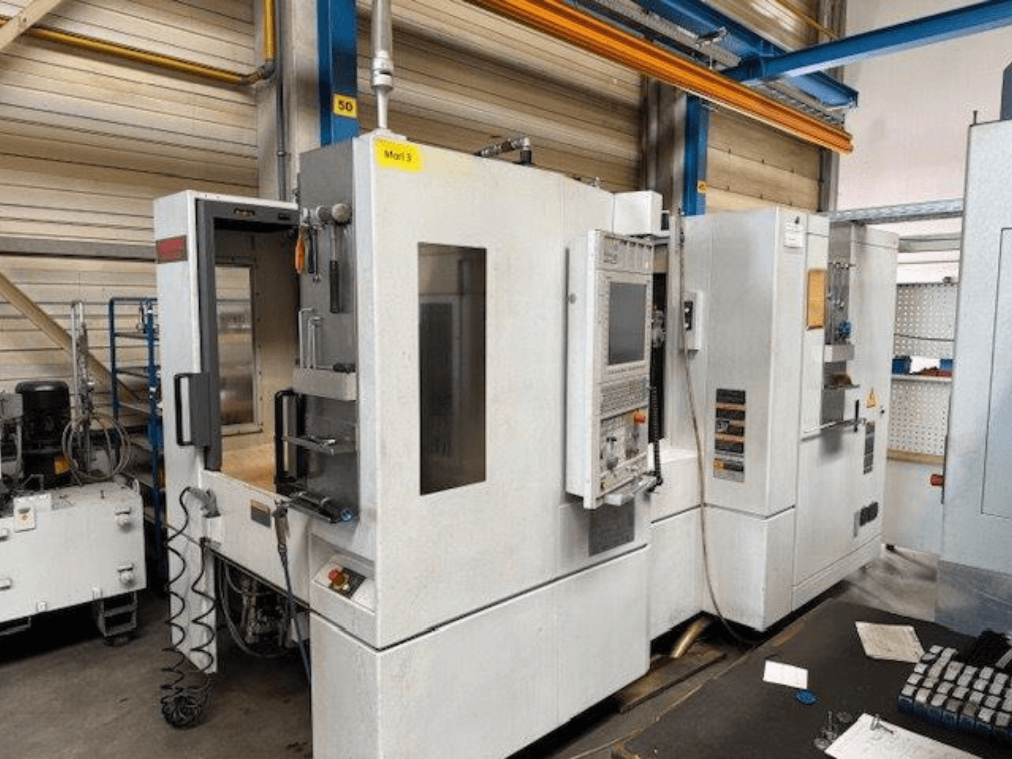 Frontvy av en MORI SEIKI NH4000 DCG horisontell fleroperationsmaskin med öppen dörr och kontrollpanelen synlig, som visar driftutrymmet.