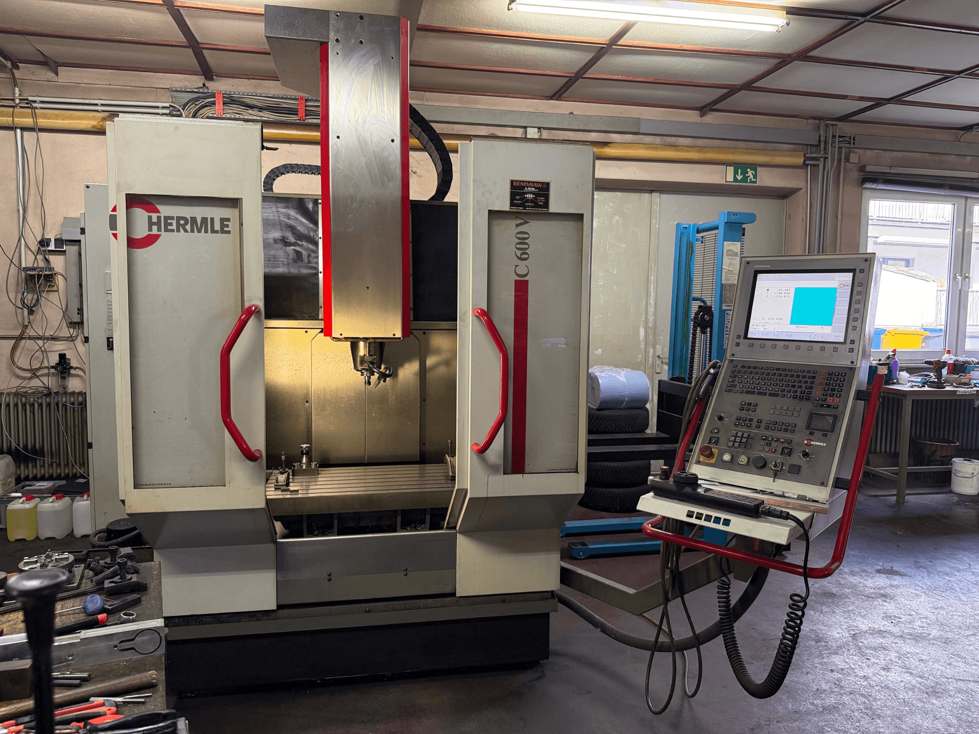 Hermle C 600 CNC-fräsmaskin framifrån, med en kontrollpanel med många knappar och ett rymligt arbetsområde.
