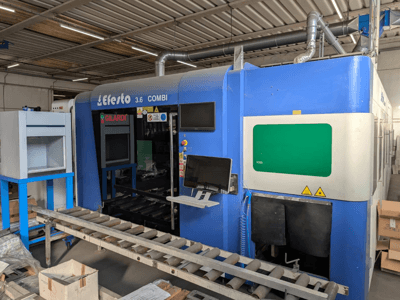 Fiberlaserskärmaskin EFESTO 3.6 COMBI, sidovy, med kontrollpanel och säkerhetsindikatorer samt blått hölje.