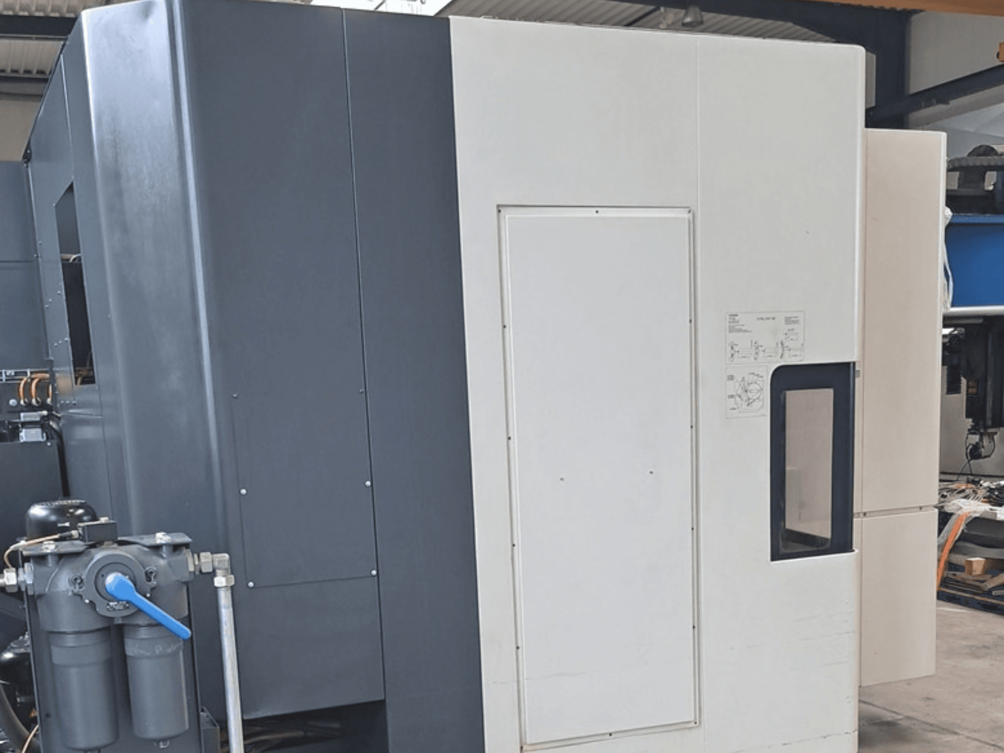 DMG MORI NHX5000 horisontellt bearbetningscenter, sidovy som visar kontrollpanelen och de mekaniska detaljerna.