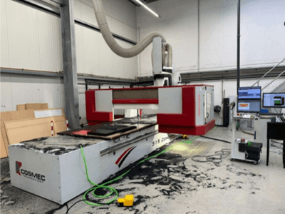 Cosmec 515 CNC-maskin i verkstad med en datorterminal, som visar en vy framifrån och damm utspridda på ytan.