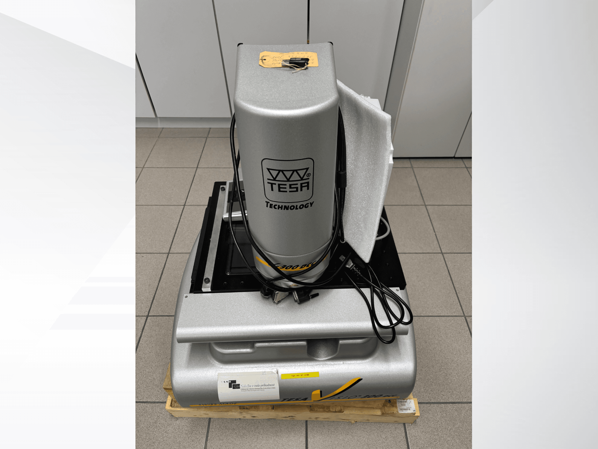 TESA Visio 300 DCC optisk mätmaskin framifrån med kablar, på en träpall, med synlig skyddsförpackning.