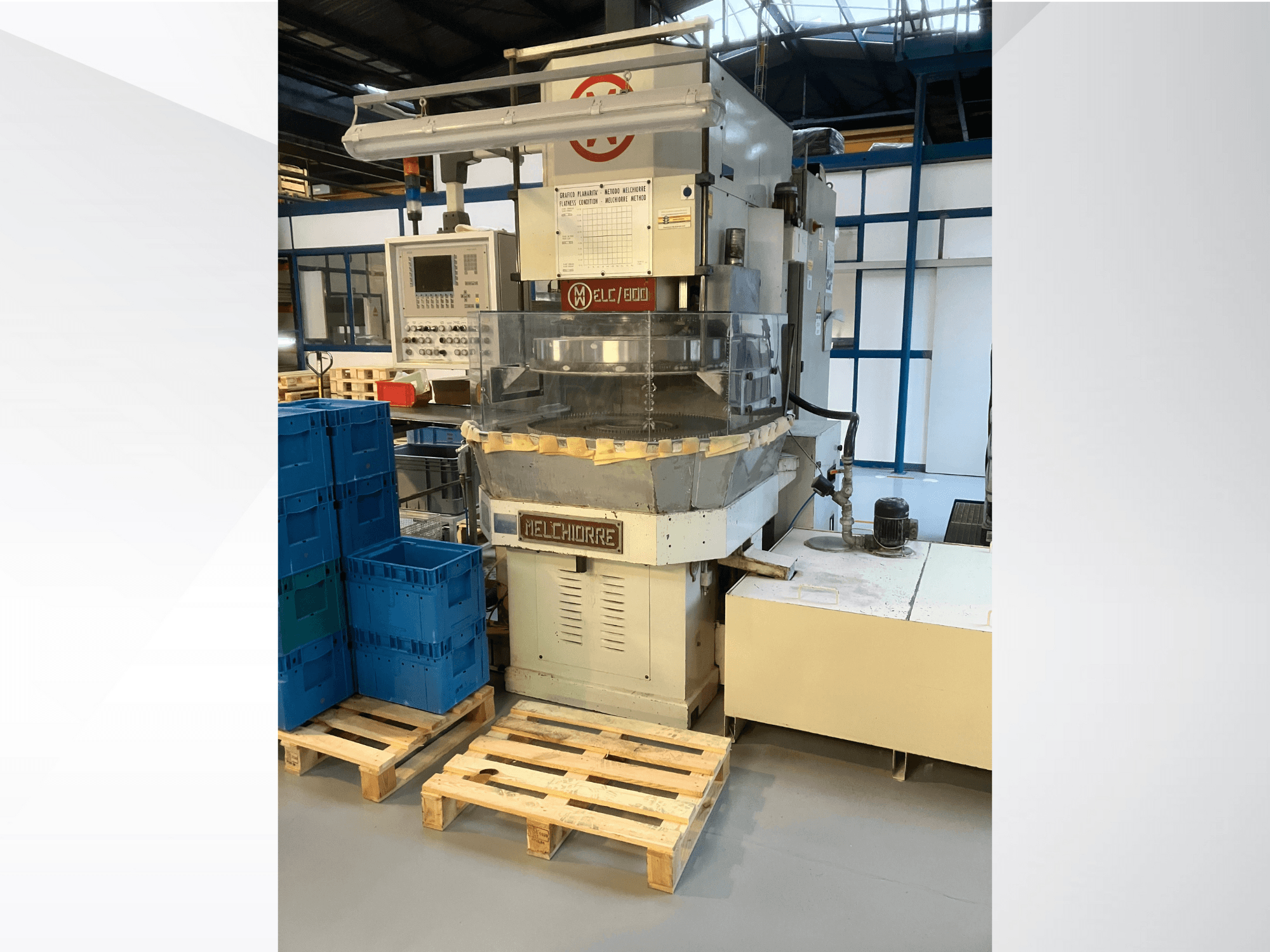 Melchiorre industrimaskin framifrån, med kontrollpanel, genomskinlig tratt och blå lådor på träpallar.