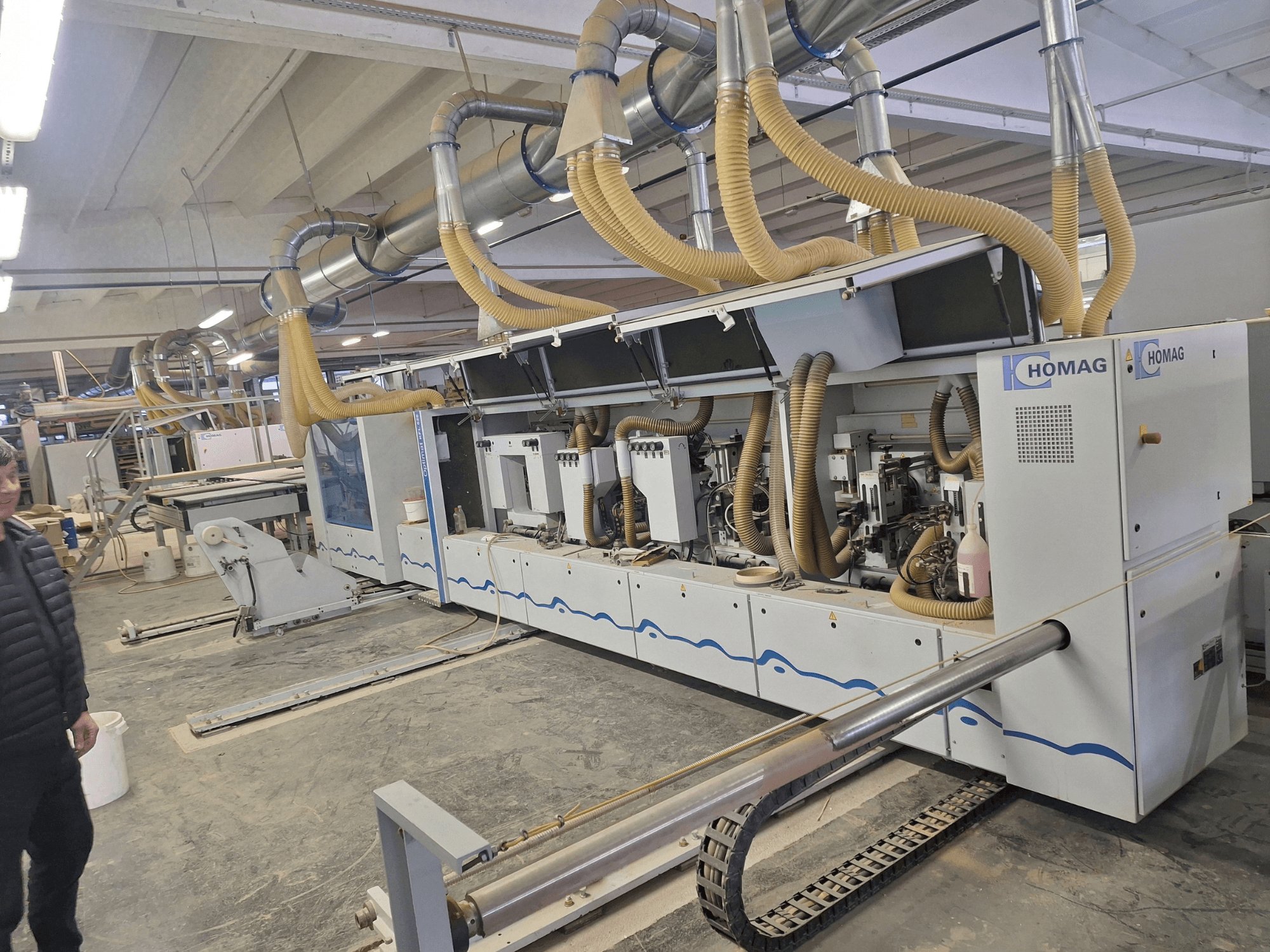 HOMAG träbearbetningsmaskin i en fabriksmiljö, framifrån med flera spindlar och dammutsugningssystem.