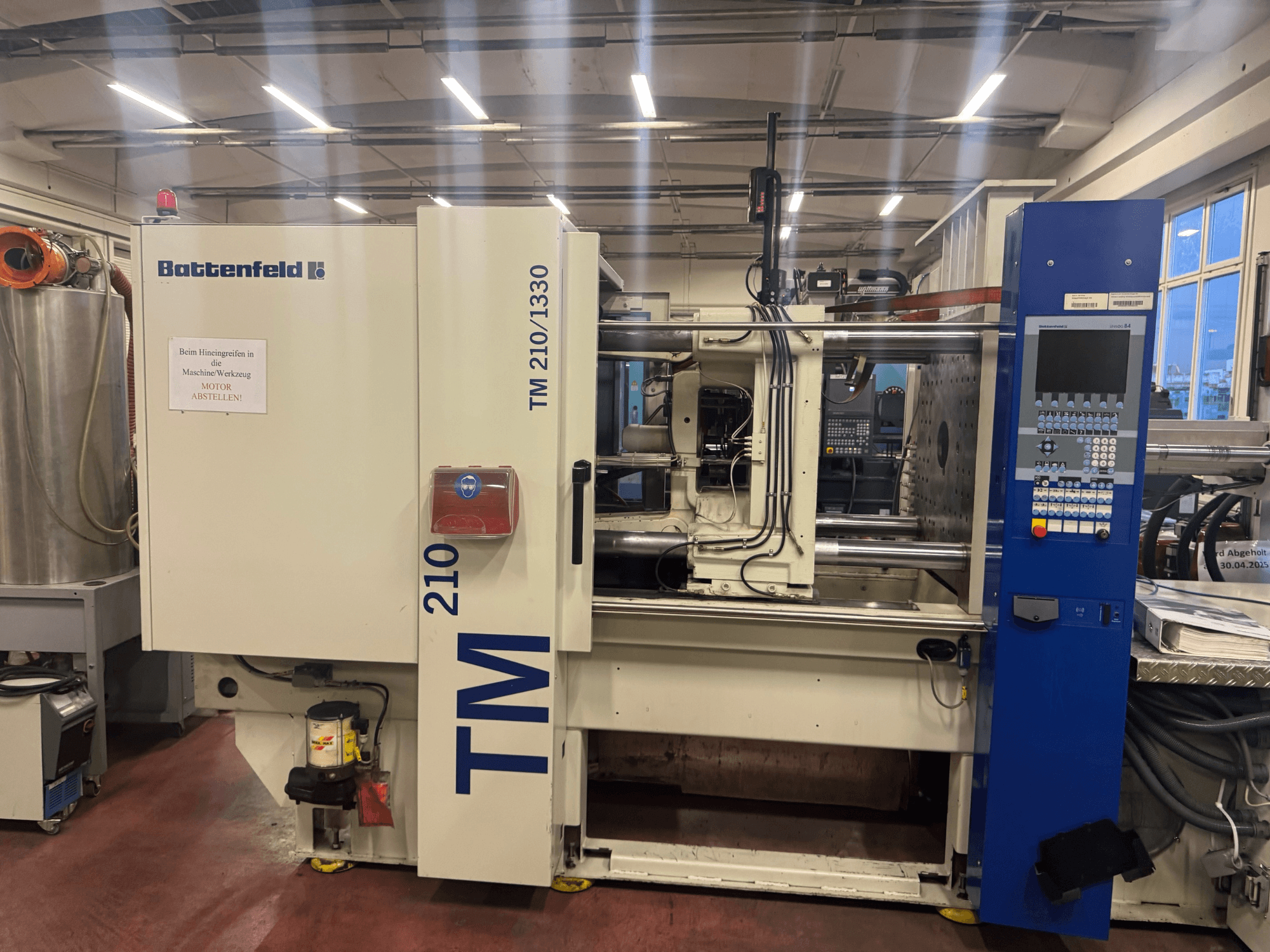 Battenfeld TM 210/1330 hydraulisk formsprutningsmaskin, framifrån, med kontrollpanel och maskinkomponenter.