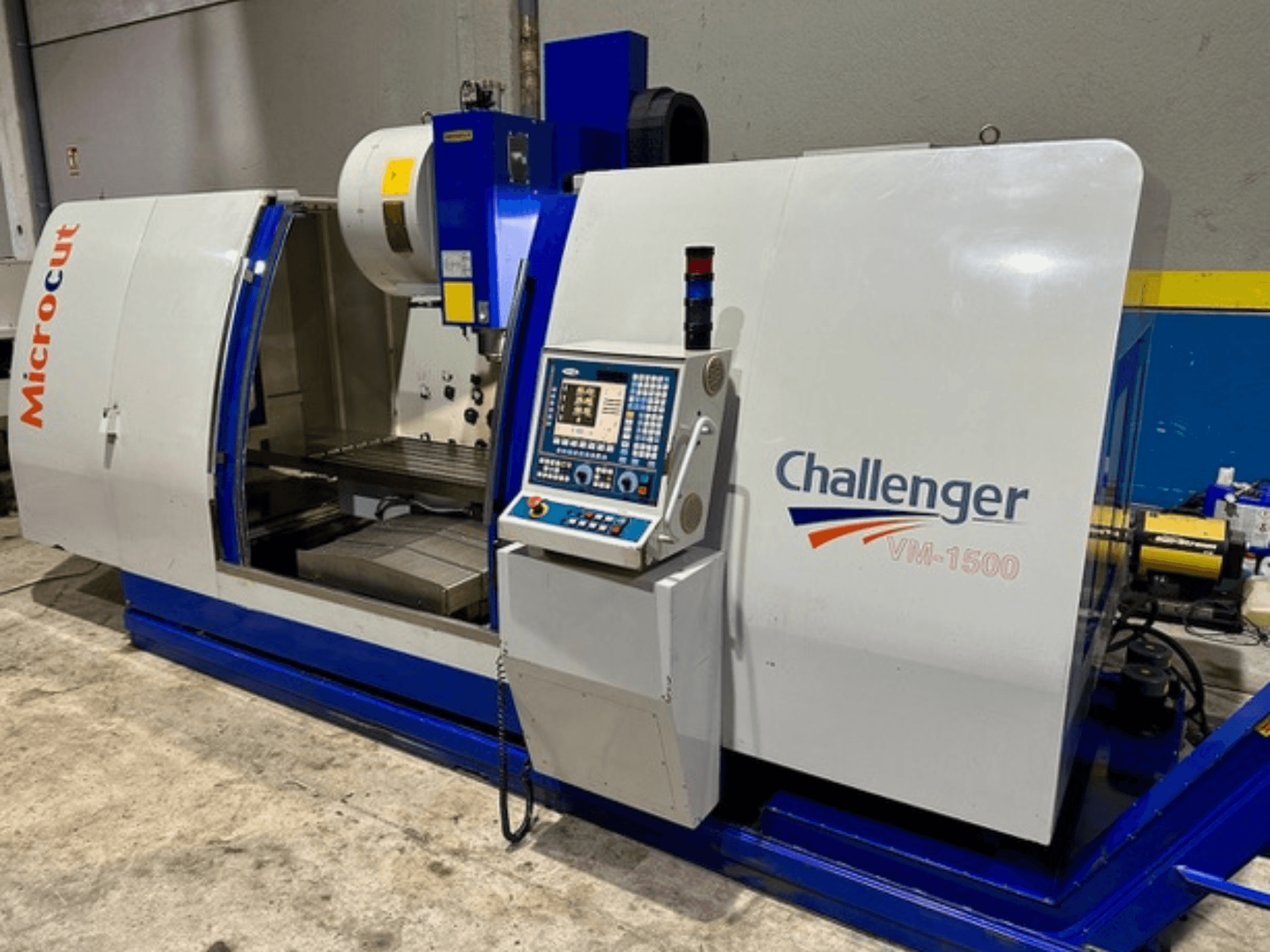 Microcut Challenger VM-1500 CNC-maskin, framifrån, med kontrollpanel, arbetsyta och en blå bas.