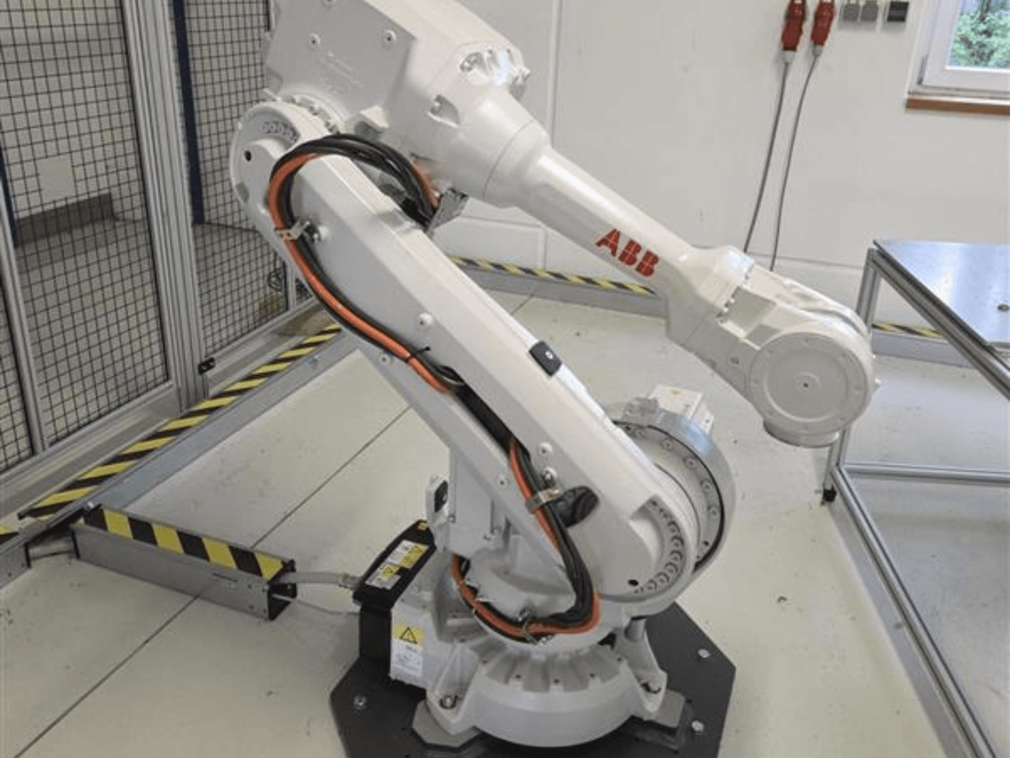 ABB IRB 4600-45/2.05-robotarm i profil, som visar dess ledade konstruktion och kablarna anslutna till basen.