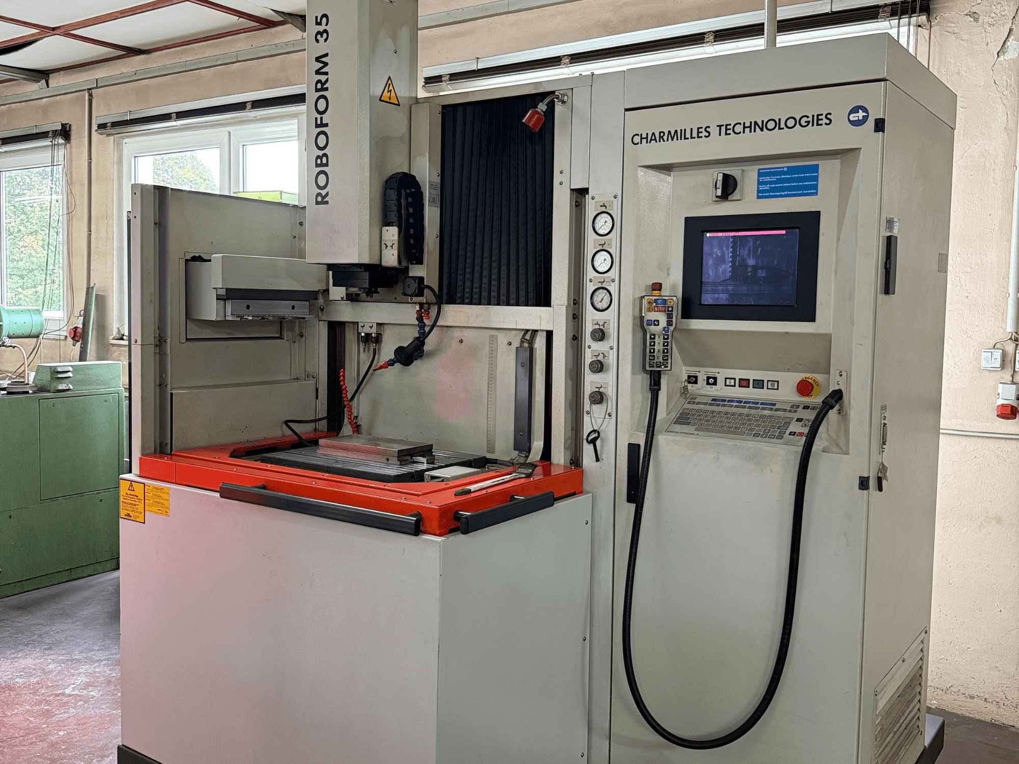 Charmilles Technologies Roboforn 35-maskin, framifrån, med kontrollpanel, monterade verktyg och säkerhetsetiketter.