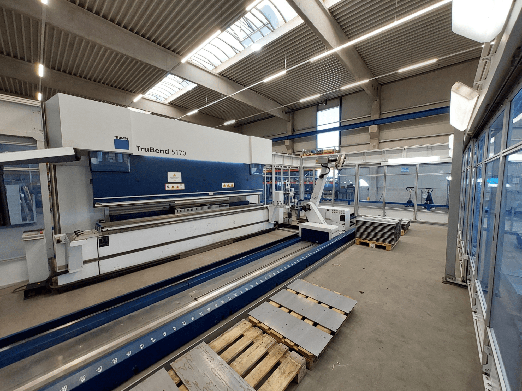TRUMPF TruBend 5170 kantpress i en verkstad, sidovy, visar bockningsverktyg och staplade plåtar på pallar.