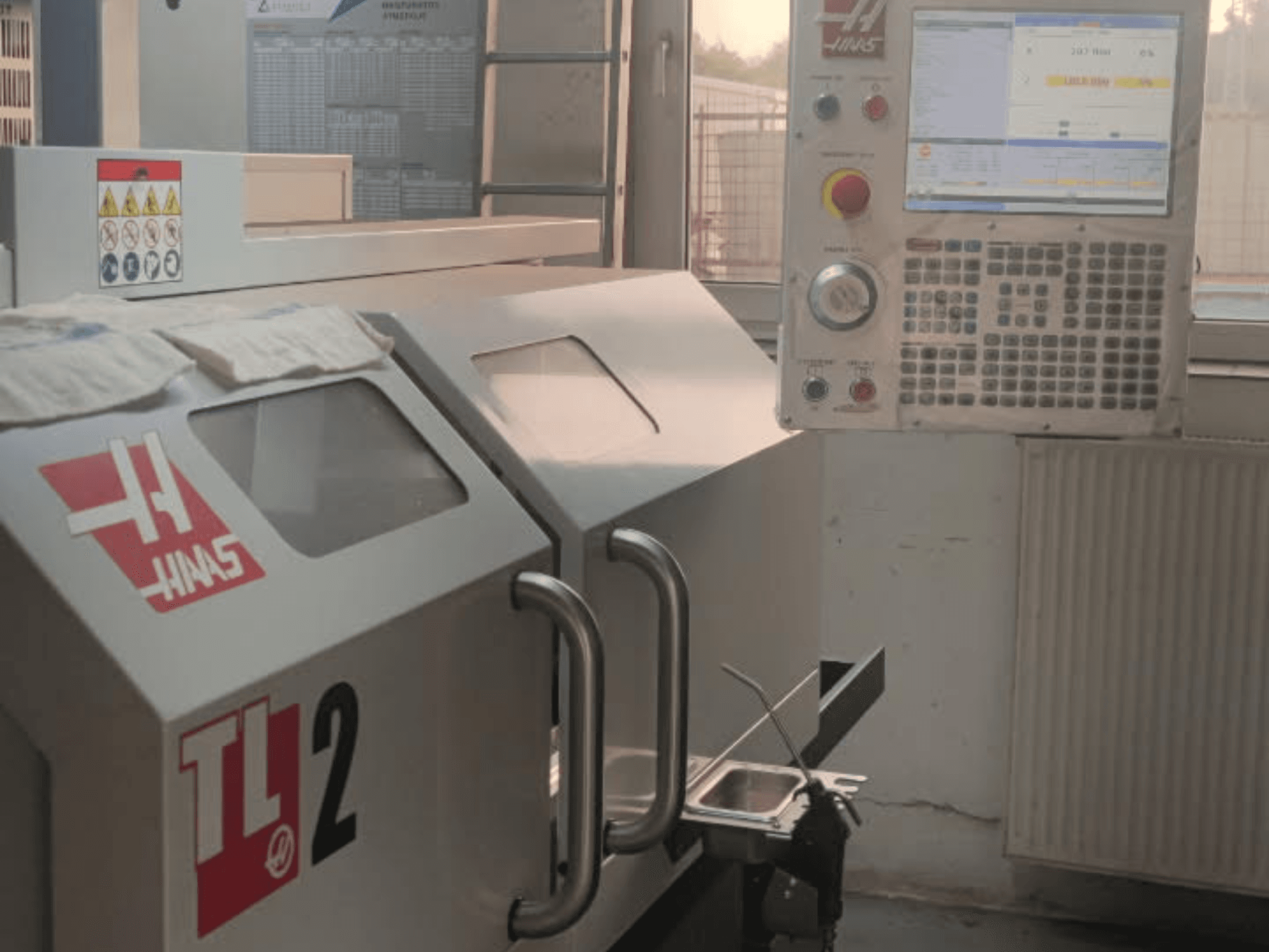 Haas TL-2 horisontell svarvmaskin framifrån, med kontrollpanel, metallhölje och säkerhetsskyltar.