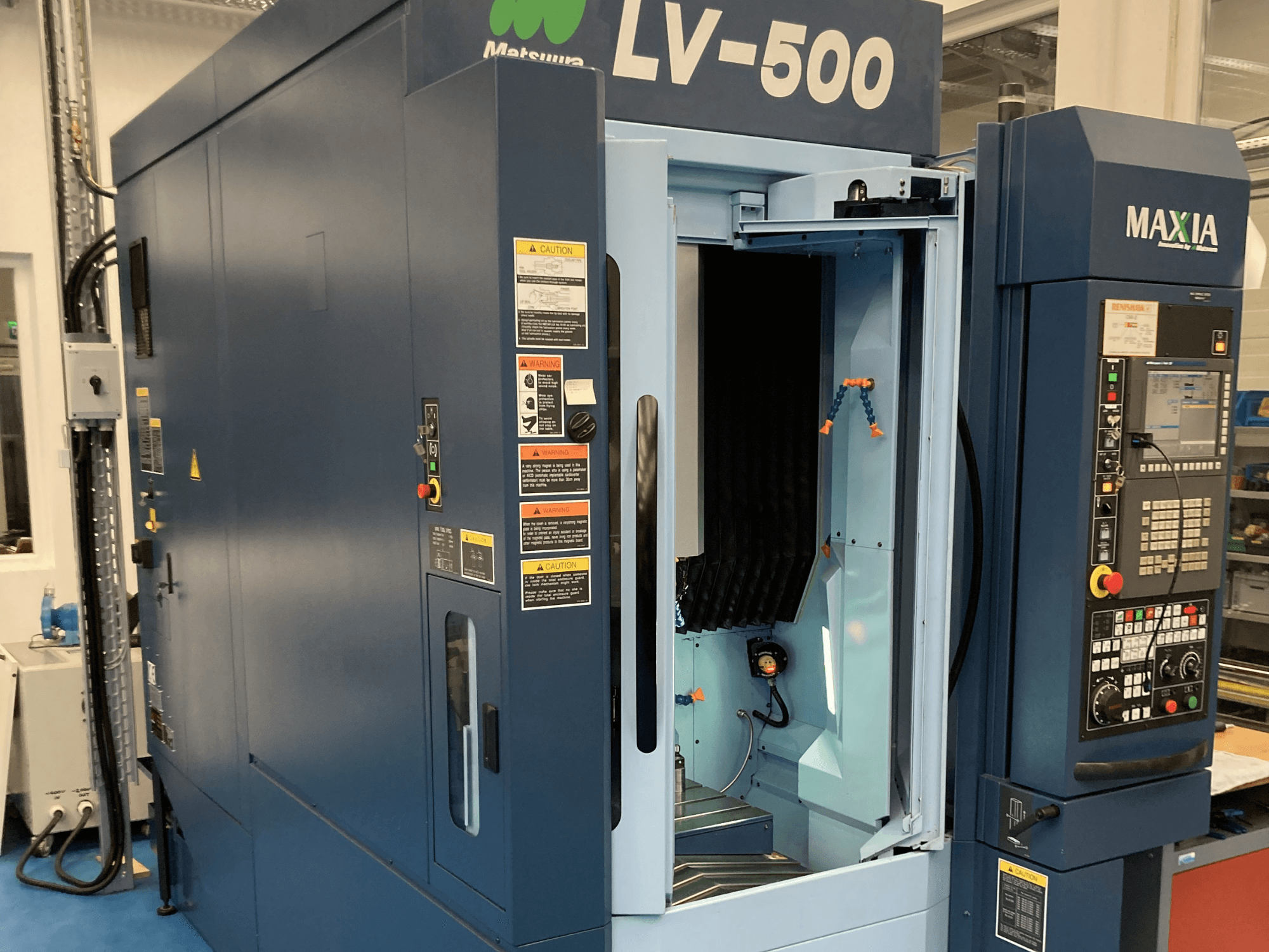Matsuura LV-500 vertikalt bearbetningscenter sett framifrån, med öppen dörr och kontrollpanel med knappar.
