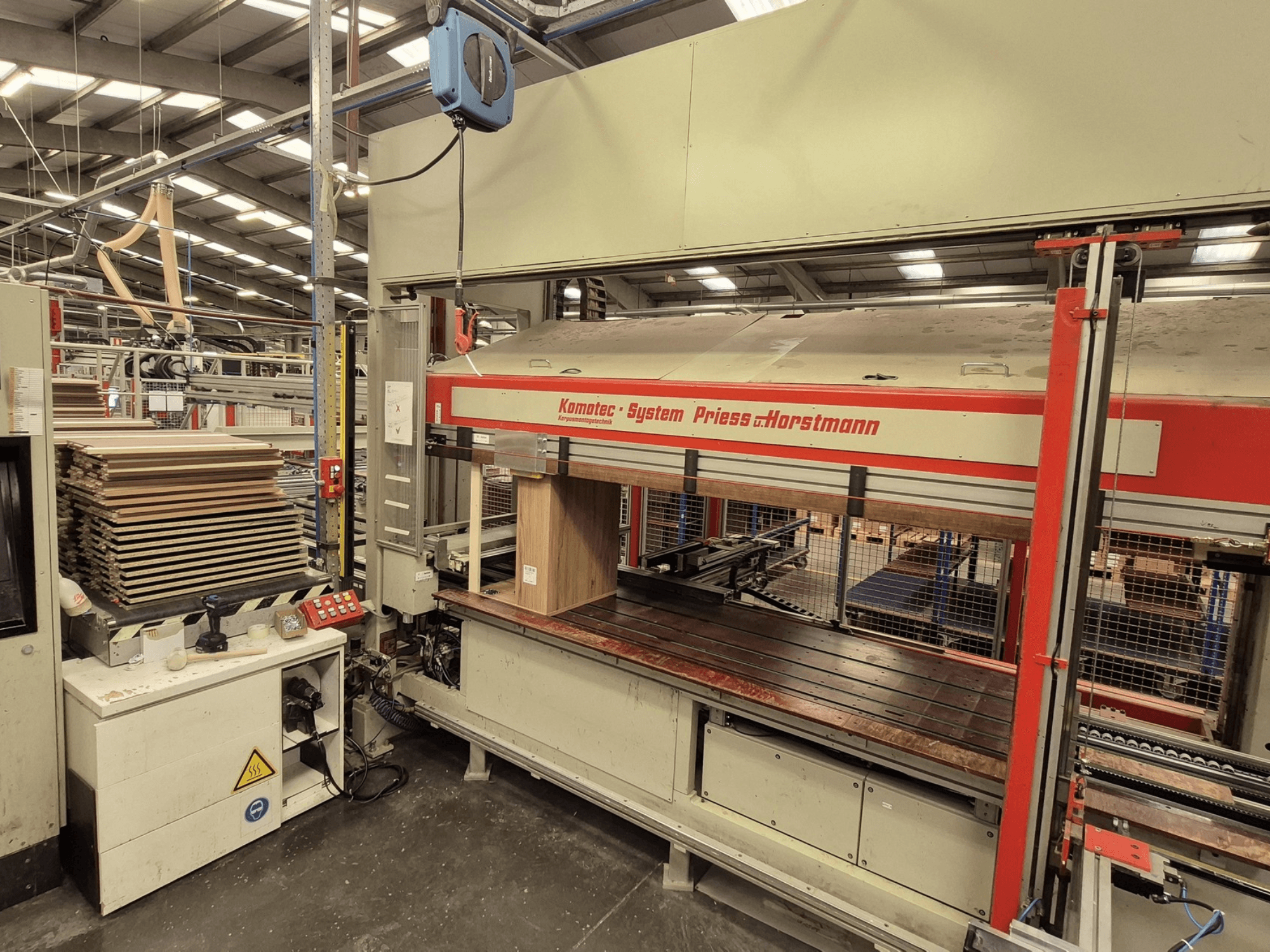 Fanérpress KP-5-CNC från PREISS U HORTSTMANN, framifrån med staplade fanérark och kontrollpanel.