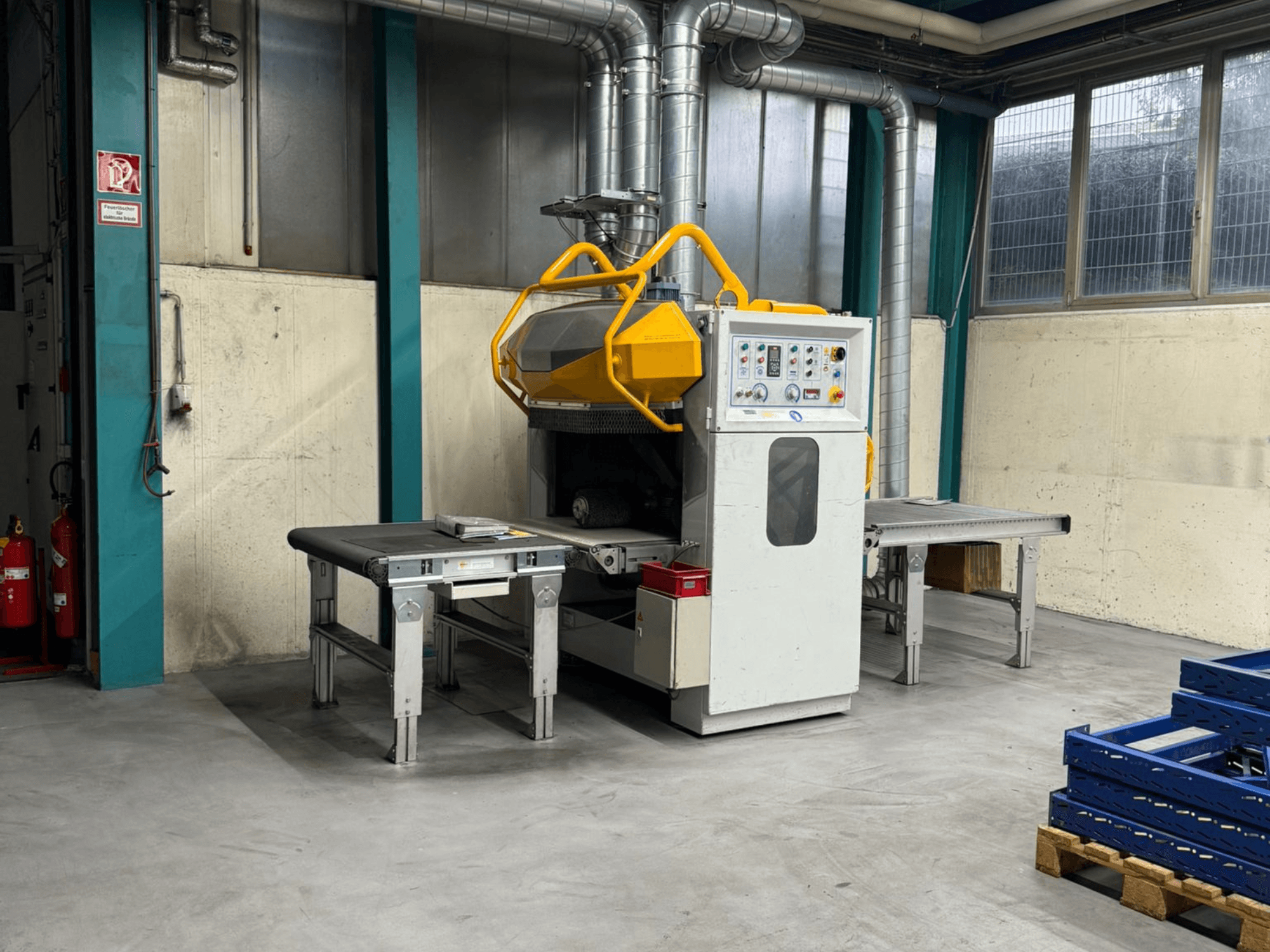 Avgradningsmaskin Fladder AUT-1000 VAC i fabriksmiljö med kontrollpanel, gult skyddsgaller och arbetsbord intill.