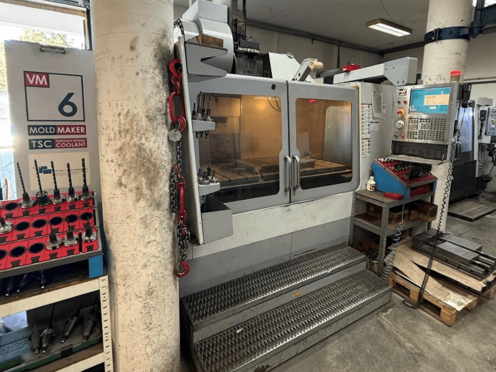 HAAS VM-6 HE vertikalt bearbetningscenter sett framifrån, där man ser manöverpanelen, kylmedelssystemet och verktygsförvaringen.