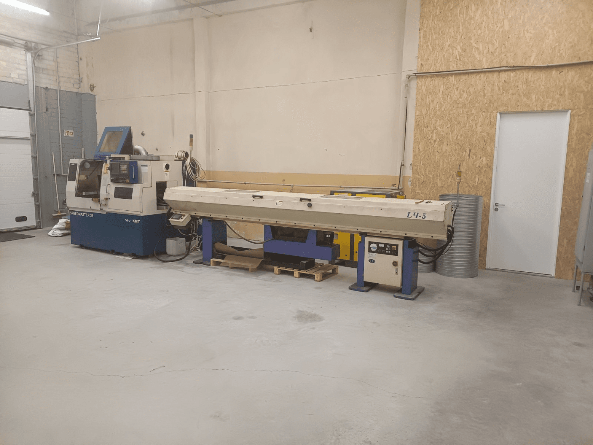 Industriverkstad med KMT Speedmaster 34-maskin och L4.5, sedd framifrån, med synliga reglage och maskiner.