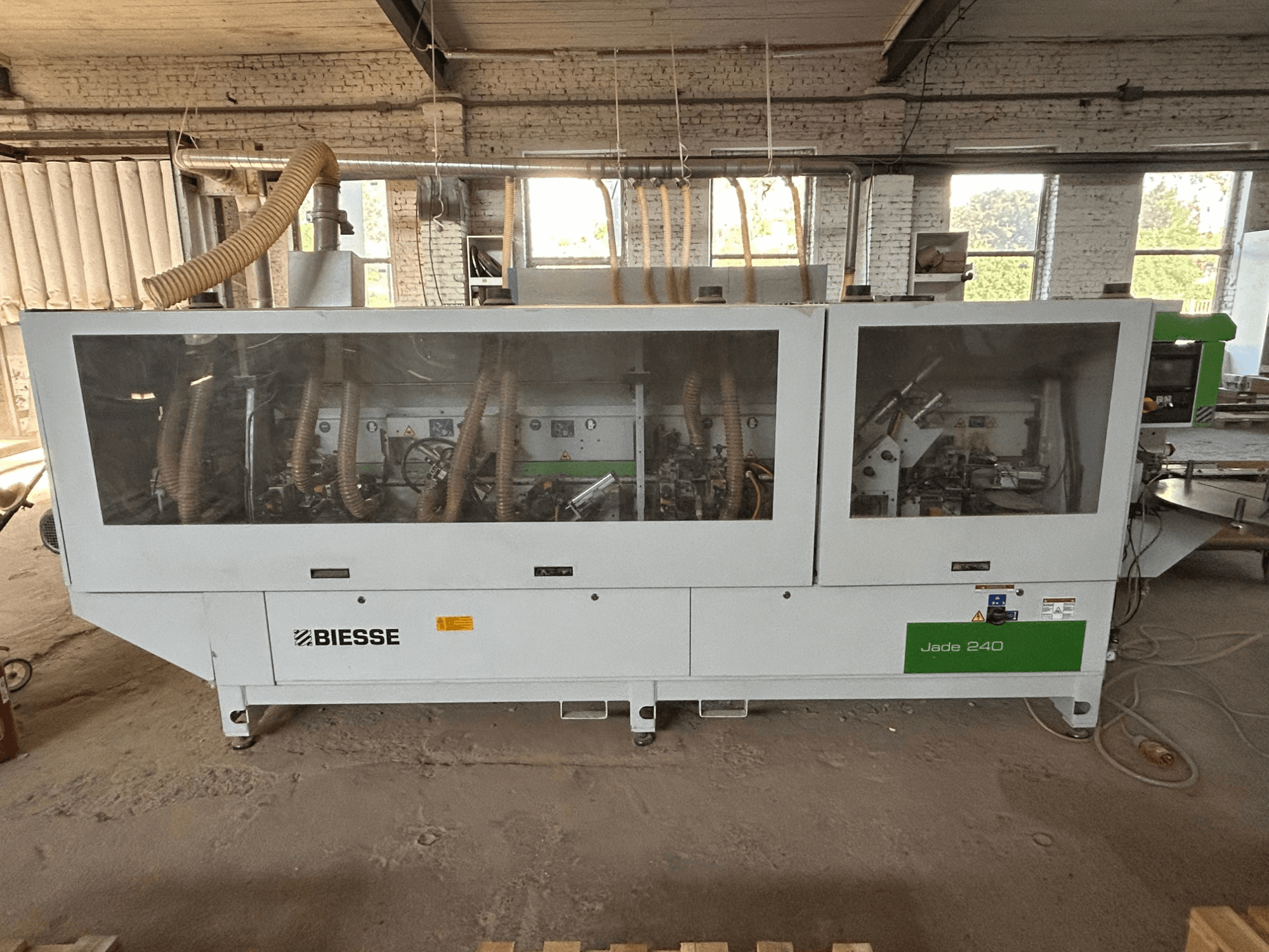 BIESSE Jade 240 kantlistmaskin i vitt och grönt, framifrån med kontrollpanelen och detaljerad inblick i maskineriet.