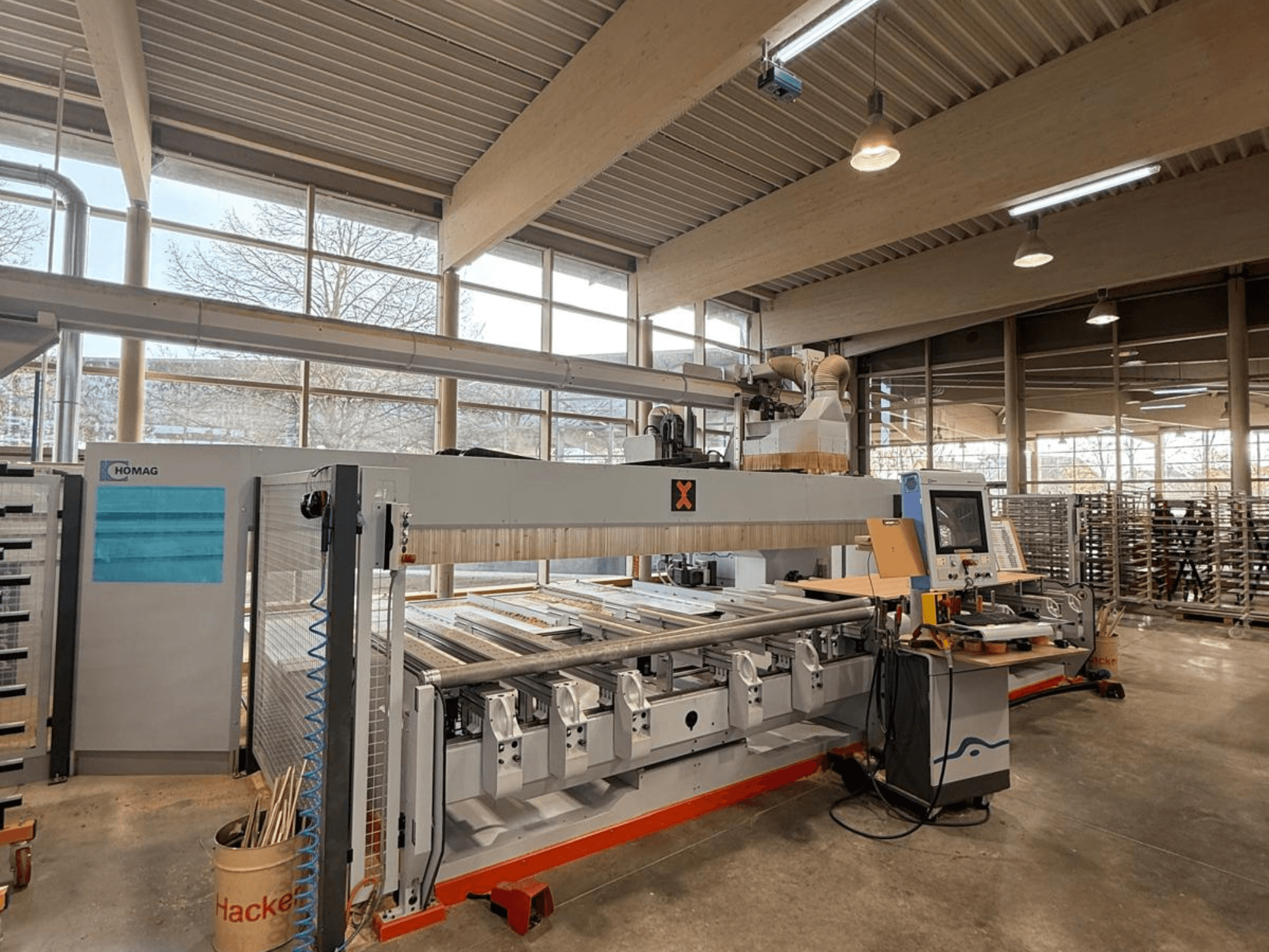 HOMAG CNC-maskin i en verkstad, vy framifrån, med kontrollpanel och flera verktygsplatser för precisionsträbearbetning.