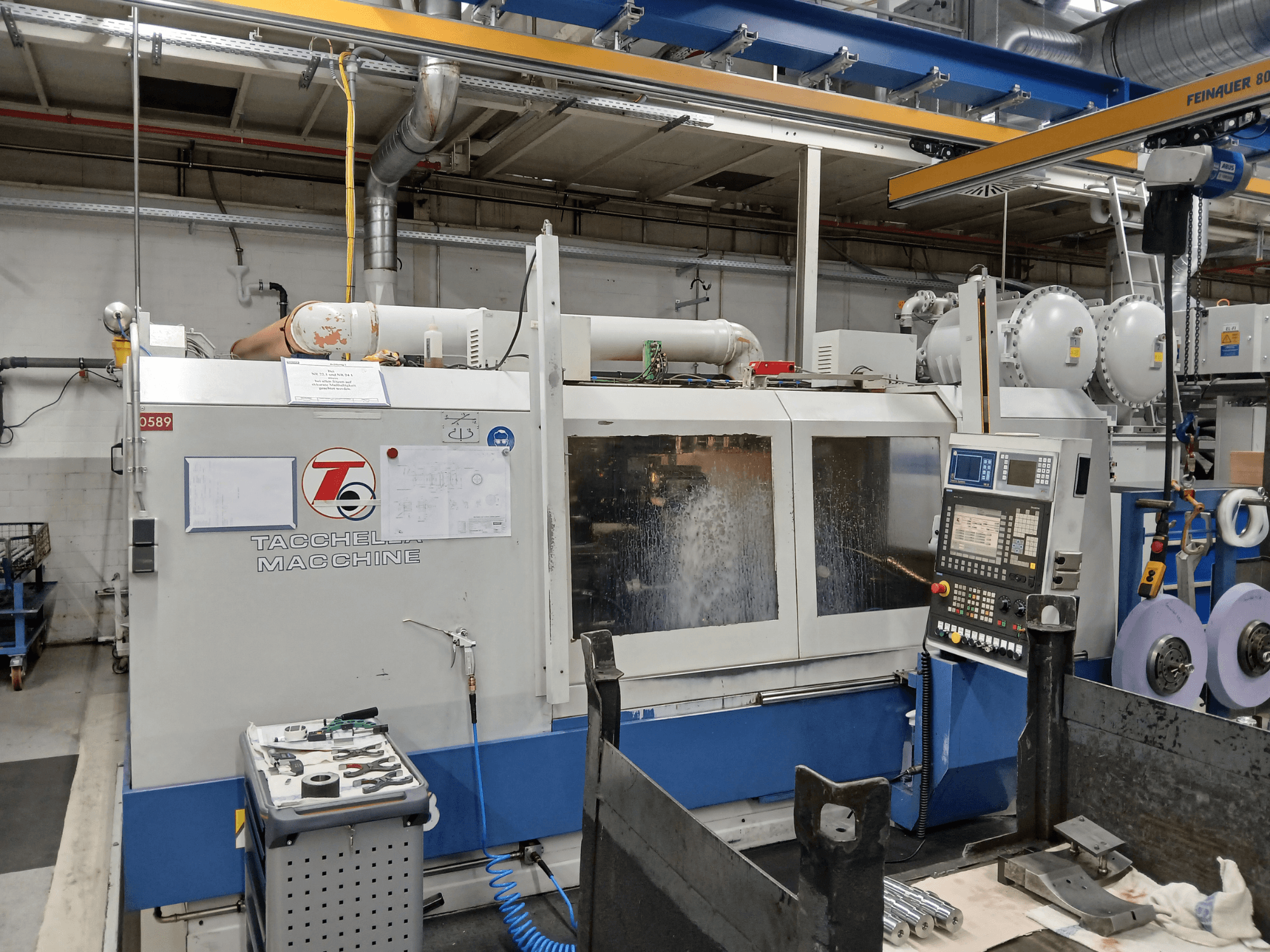 Tacchella bearbetningscenter sett framifrån, med kontrollpanel och verktyg synliga. Kylvätska sprutar under drift.