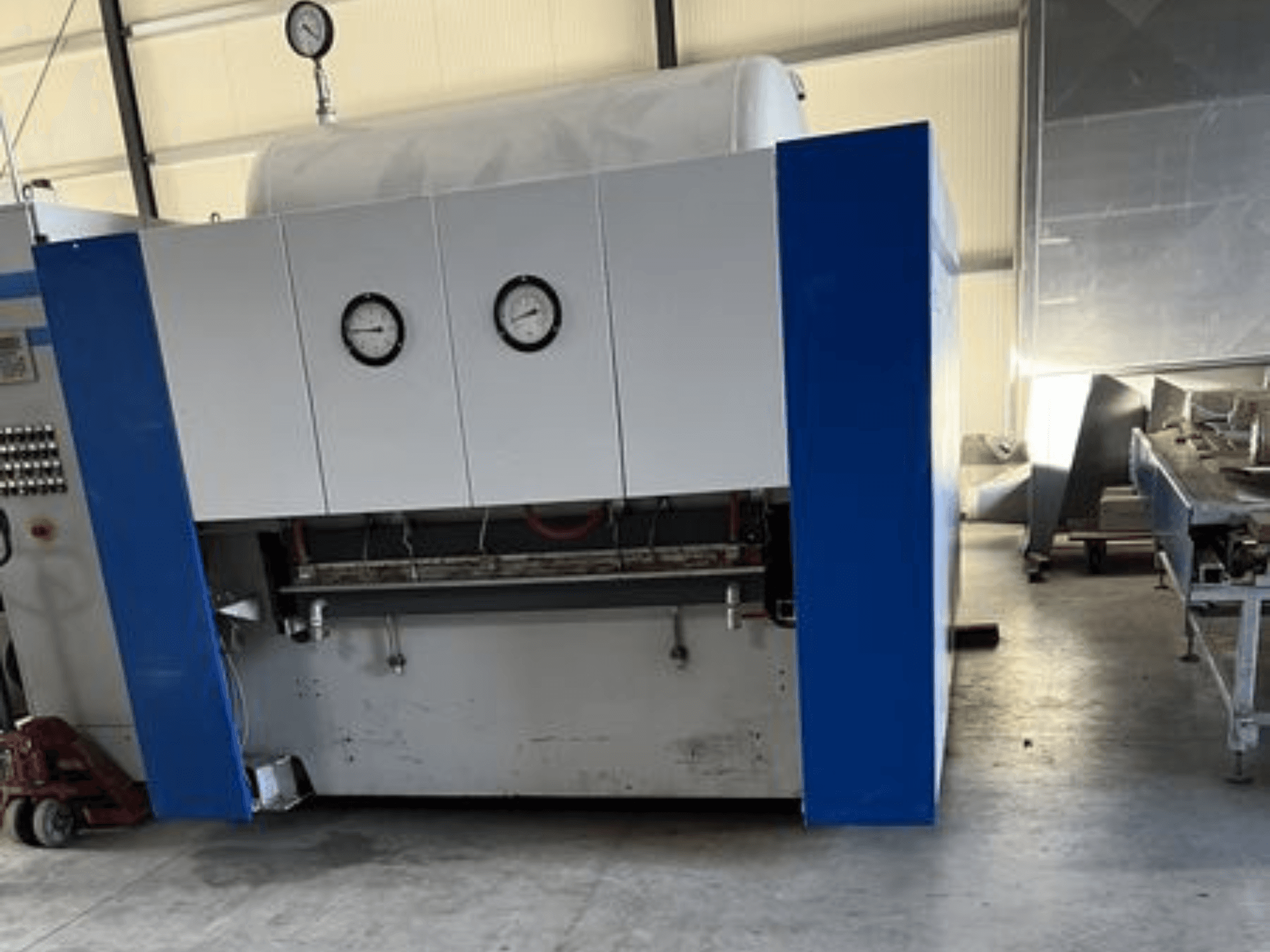 Blåvit industrimaskin med två tryckmätare, vy framifrån, med kontrollpanel och tillhörande utrustning.