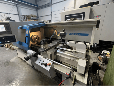 CNC-svarv DUS 400 ti framifrån, med kontrollpanel, verktygshållare och upplyst arbetsyta.